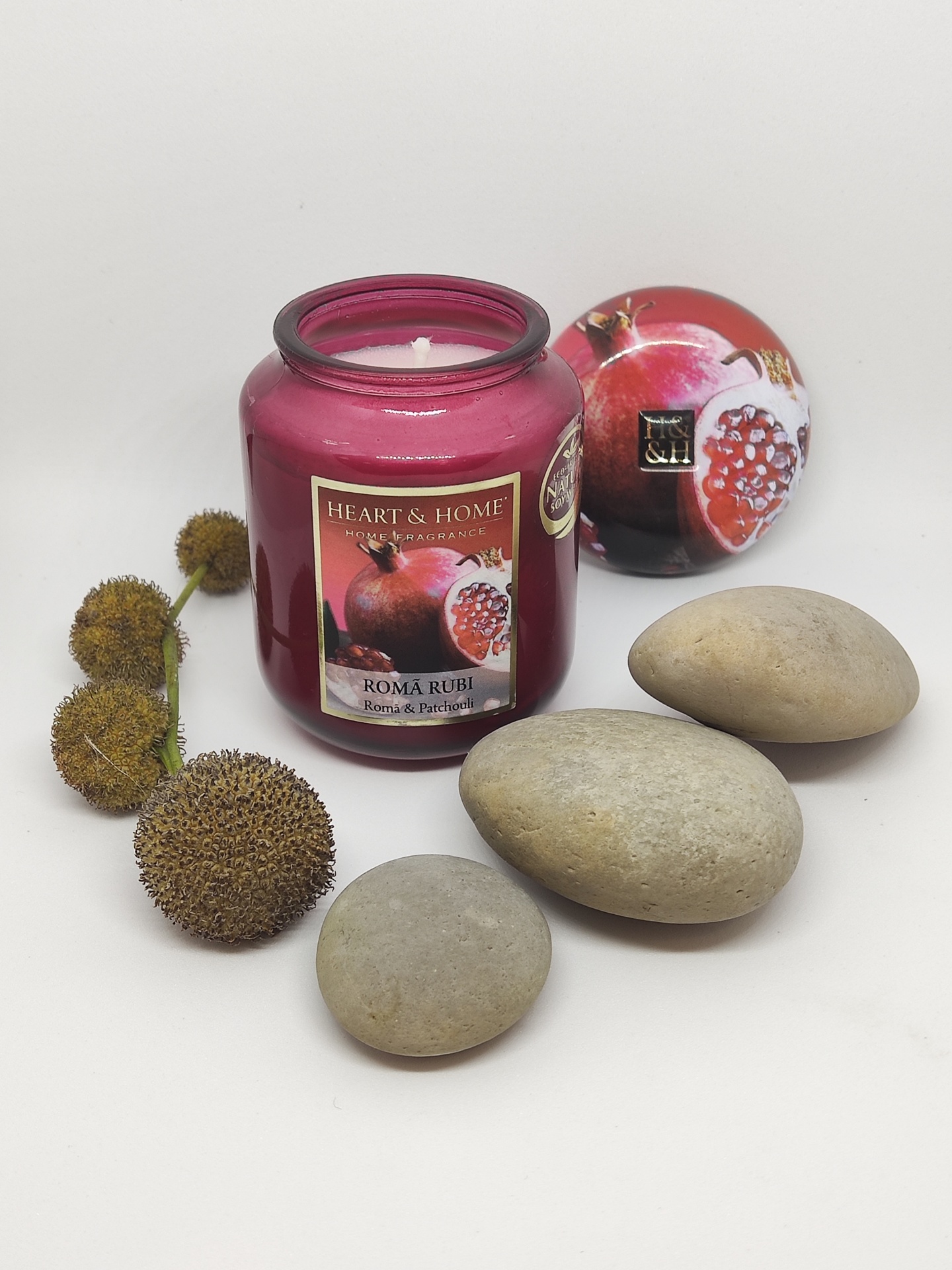 Vela vermelha em frasco de vidro com flor seca, pedras e caixa redonda decorada com romã.