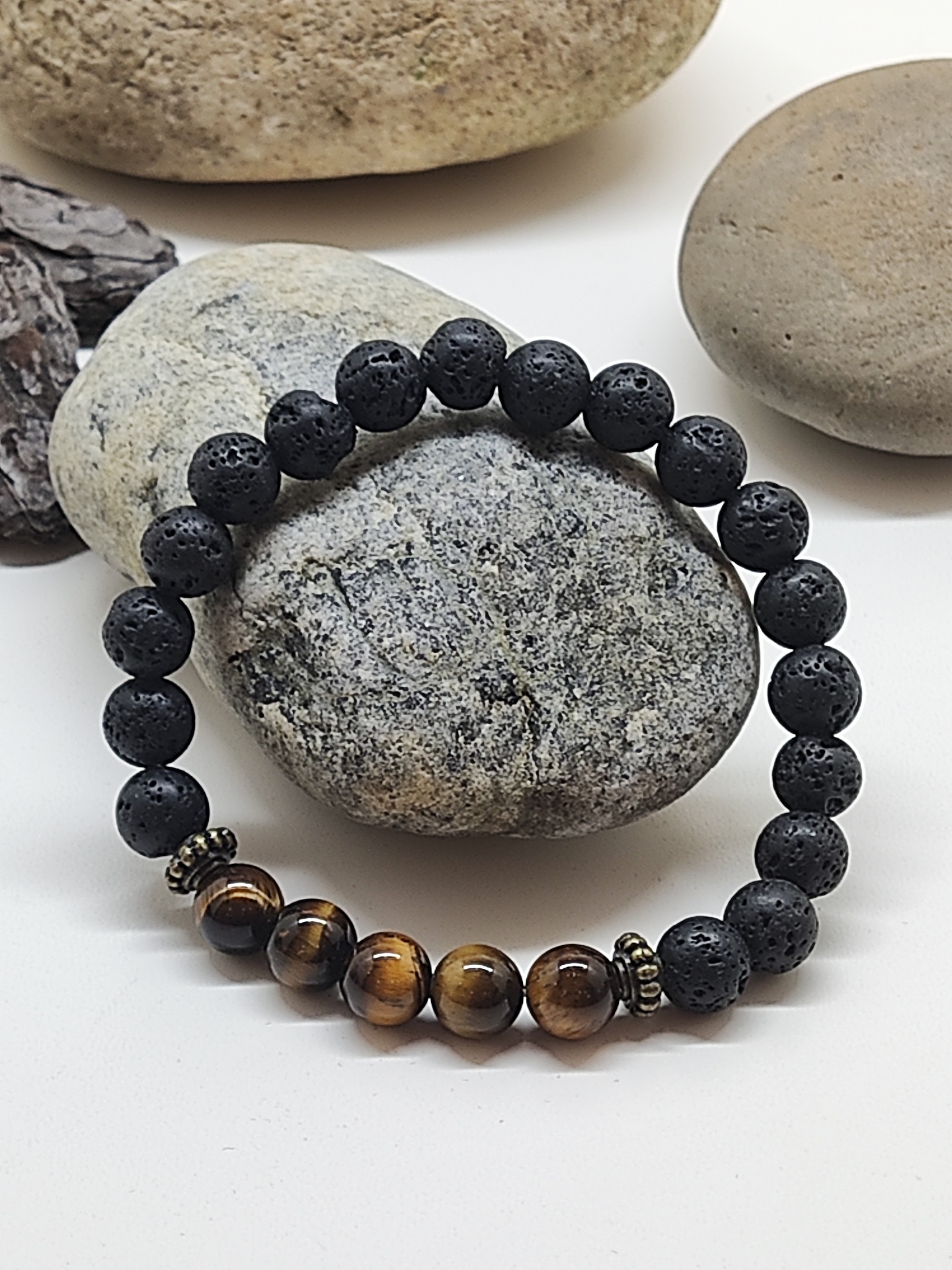 Pulseira de contas pretas e marrons sobre pedras cinzentas