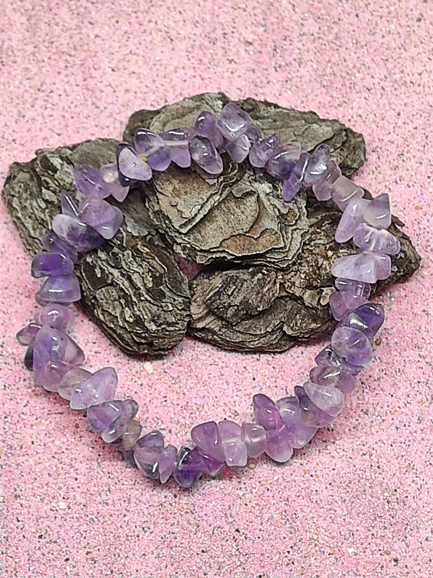 Pulseira de pedras roxas em casca sobre fundo rosa