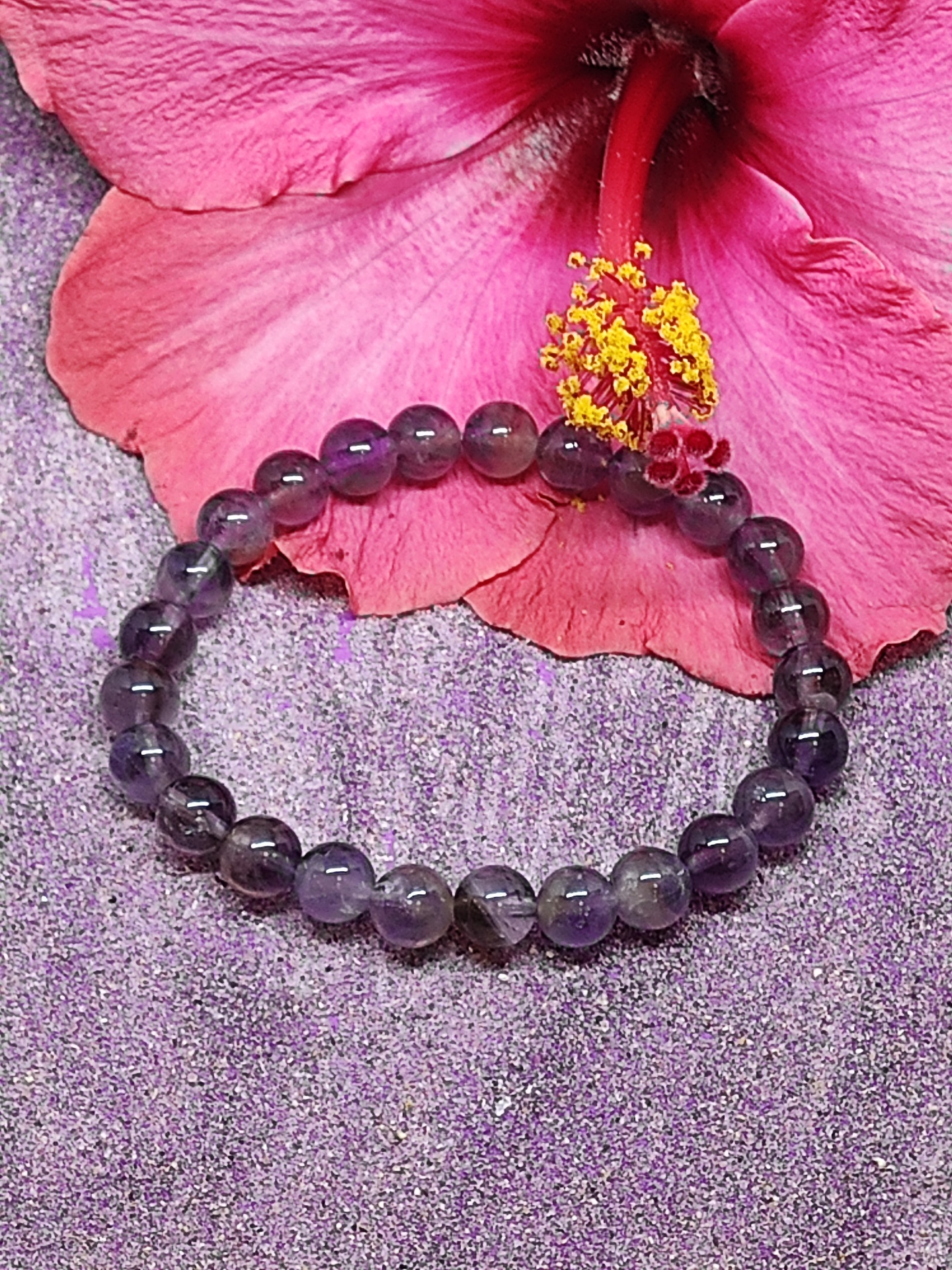 Pulseira de ametista roxa com flor hibisco cor-de-rosa e amarelo ao fundo