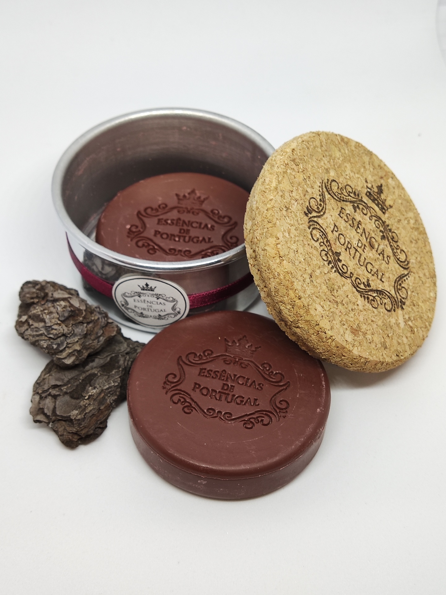Sabonete redondo castanho com texto ESSENCIAS DE PORTUGAL em lata metálica com tampa de cortiça