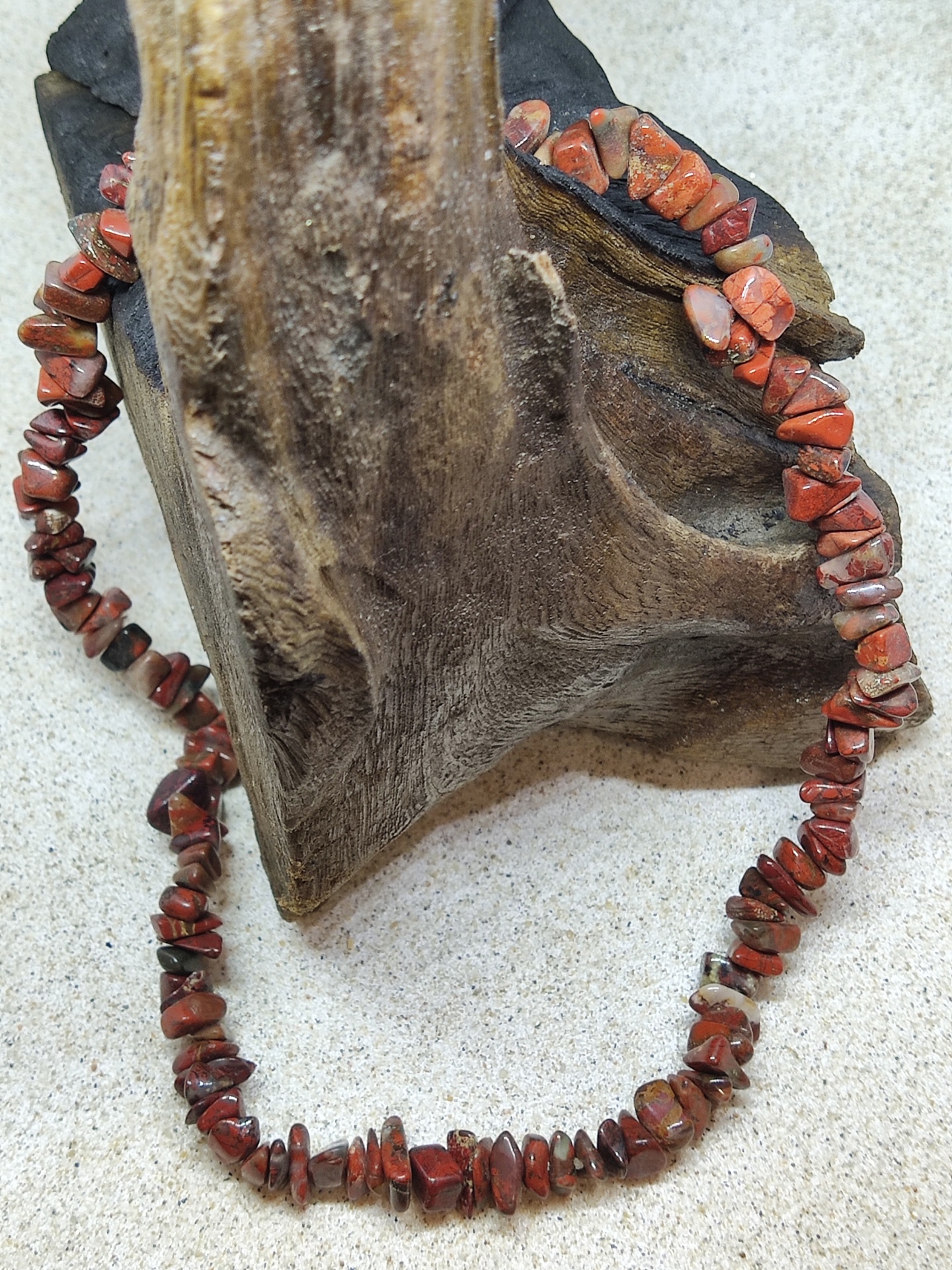 Colar de pedras vermelhas e castanhas sobre madeira escura rústica