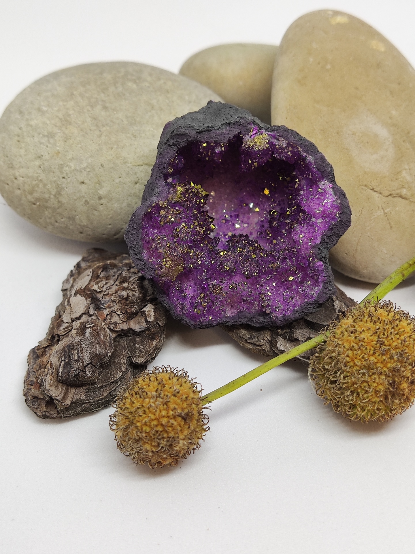 Pedras decorativas com geode roxa e esfera amarela sobre fundo branco
