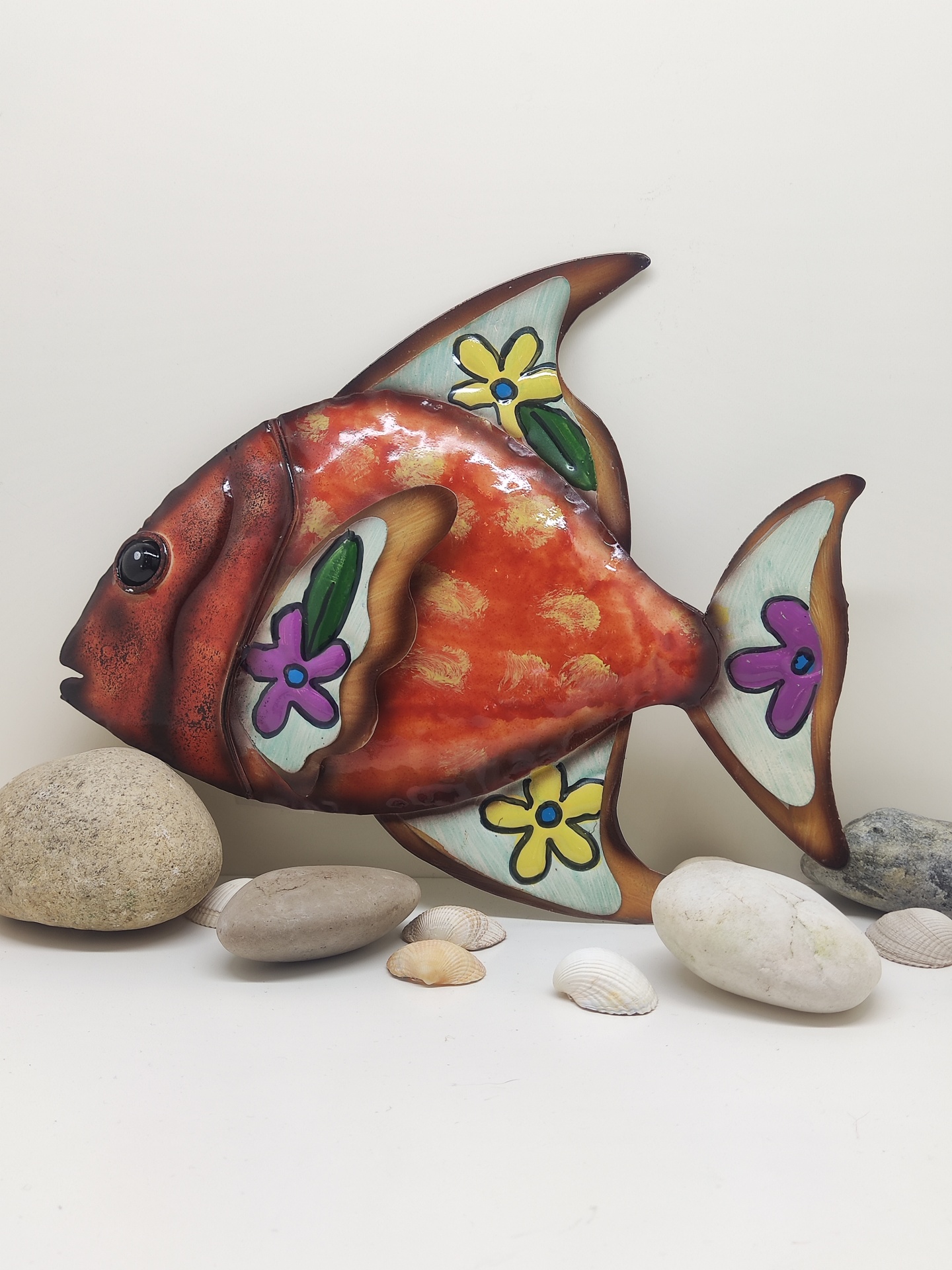 Peixe decorativo colorido com flores, pedras e conchas em fundo branco
