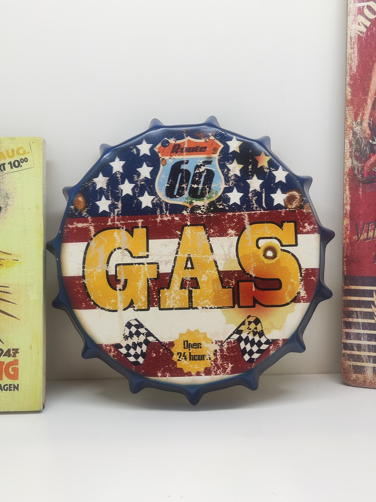 Placa decorativa em forma de tampa de garrafa com texto 'GAS' e design em vermelho, branco e azul.