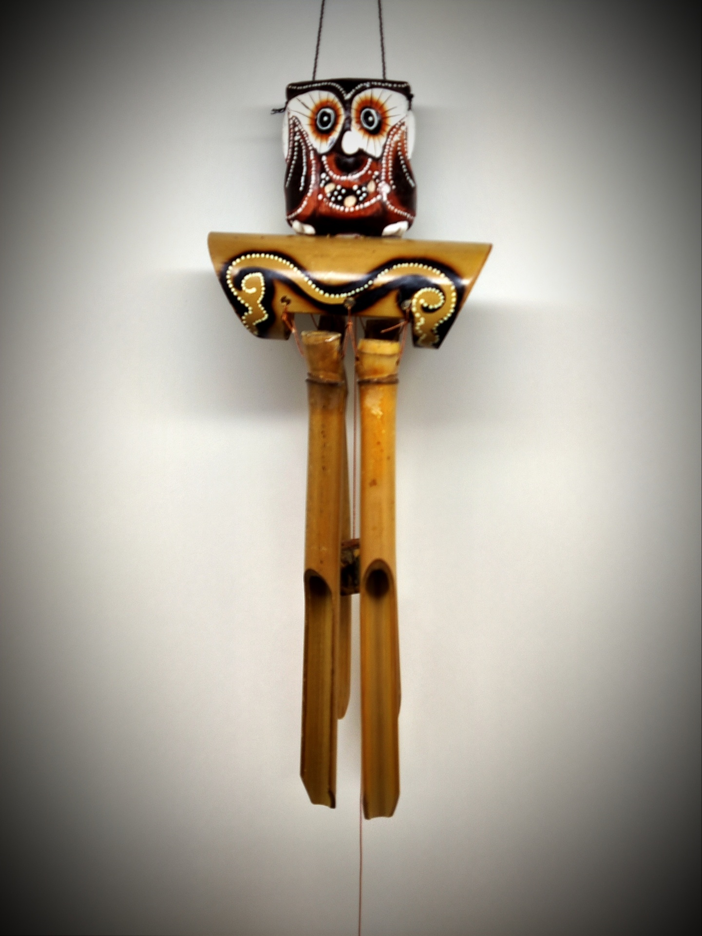 Móbile pendurado com cabeça de coruja e tubos de madeira clara