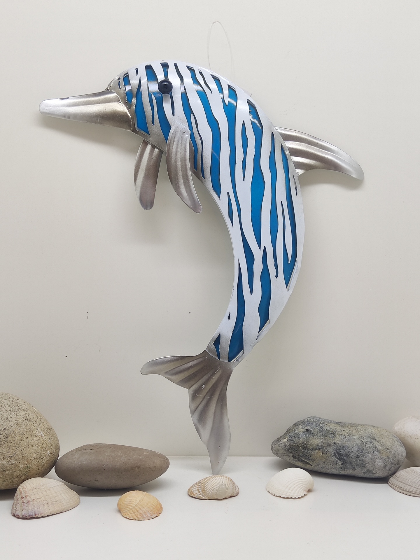 Figura de golfinho metálico azul e branco com pedras e conchas