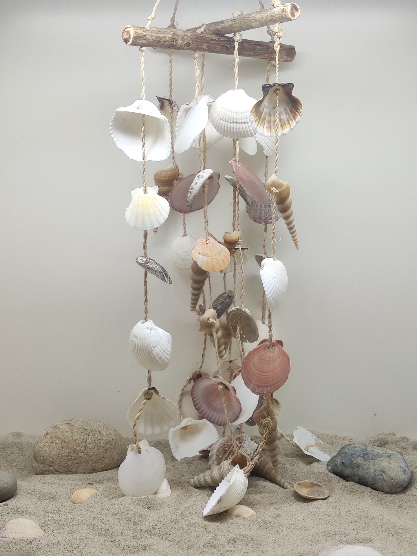 Móbile decorativo de conchas penduradas num galho de madeira