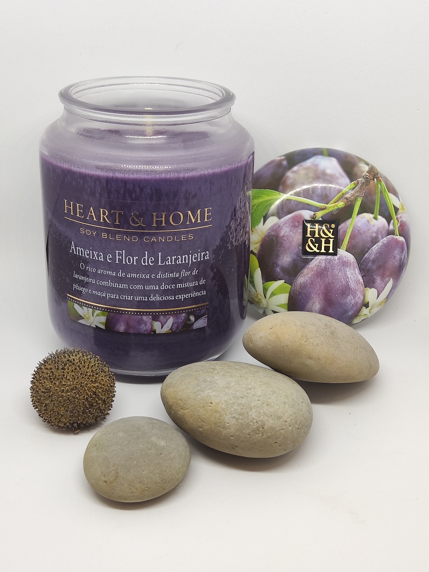 Vela aromática roxa em frasco de vidro com tampa decorativa e pedras cinzentas