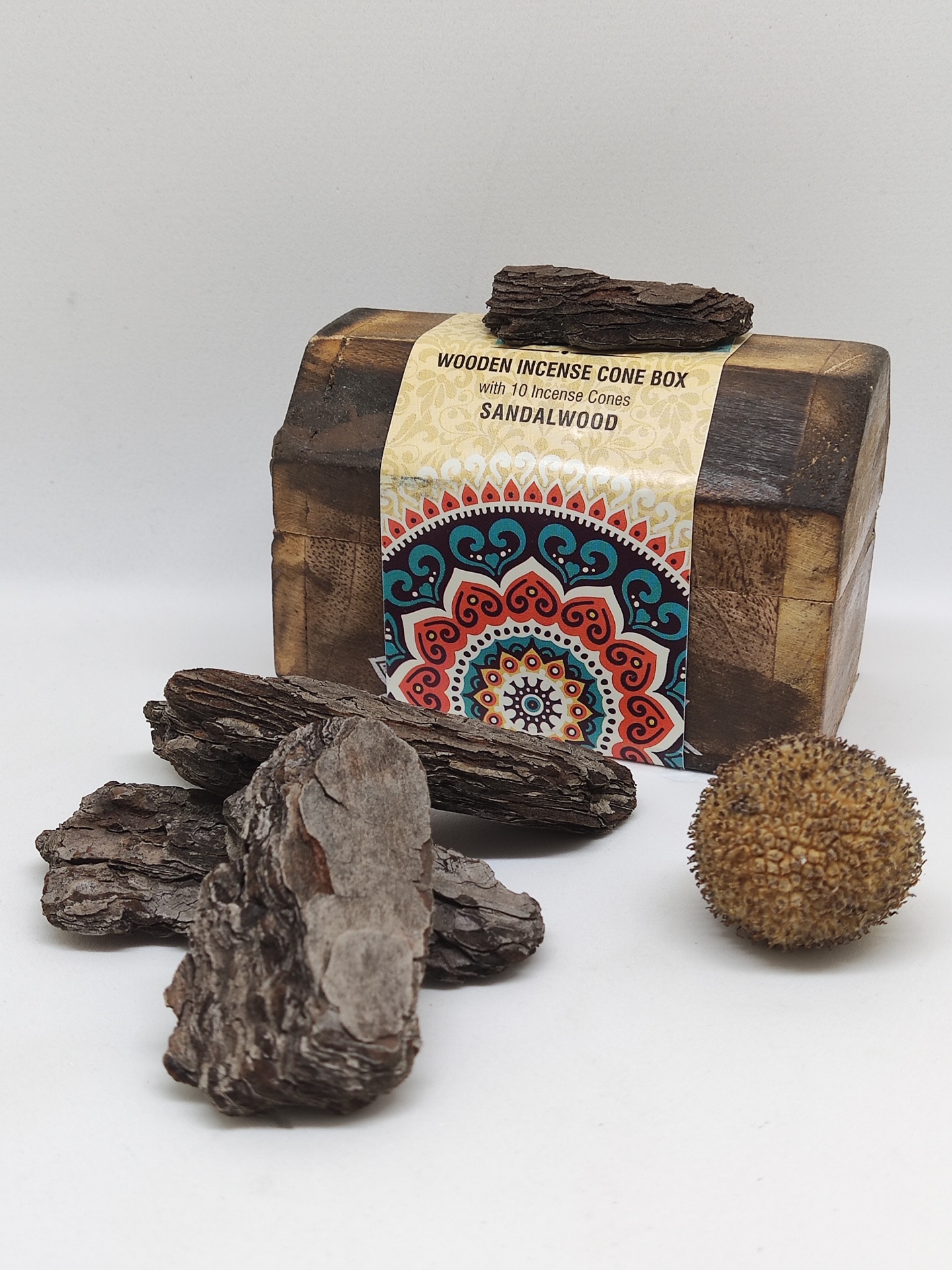 Caixa de incenso de madeira com rótulo Sandalwood, casca rija e bola natural em fundo branco.