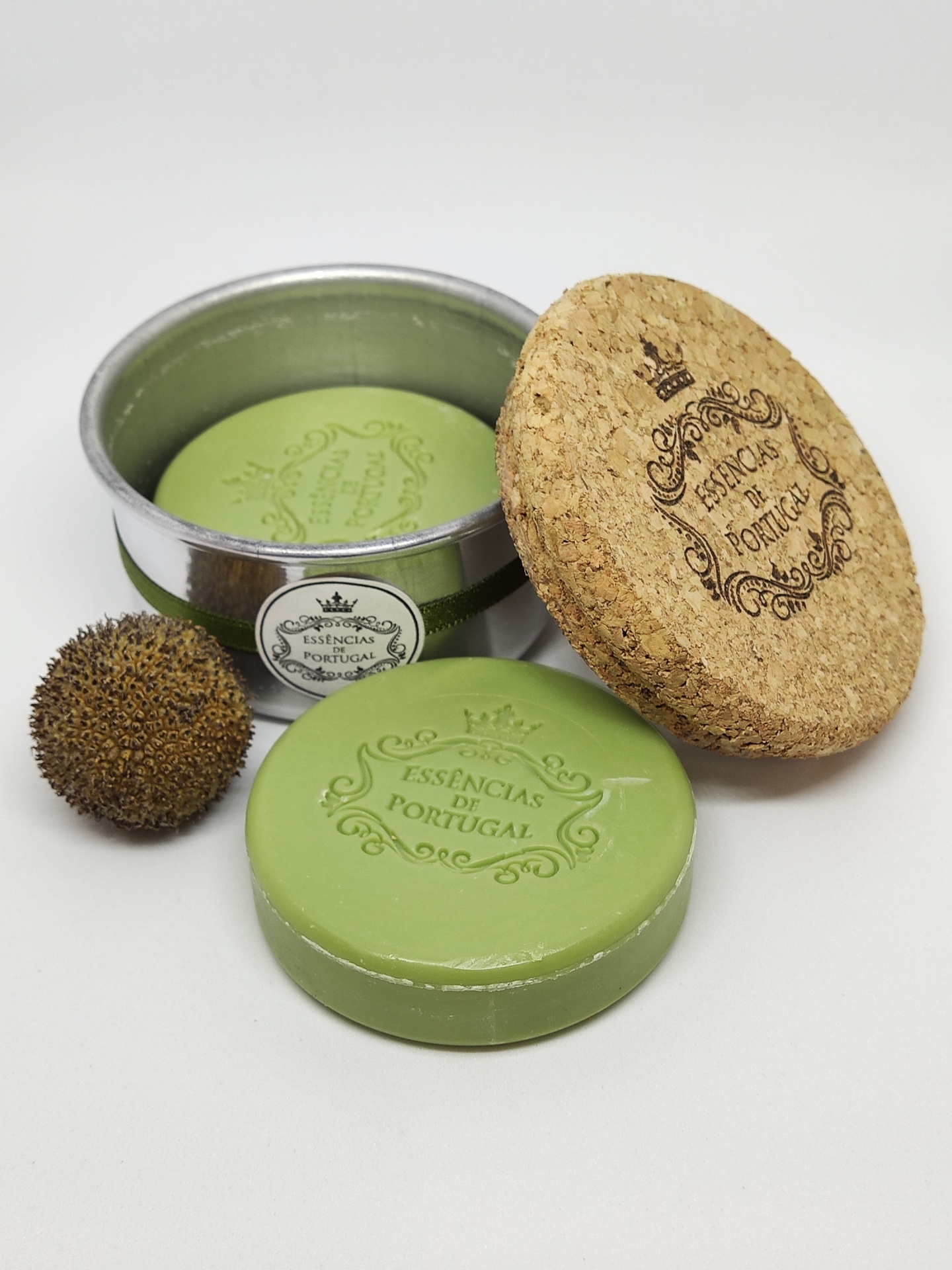 Sabonete verde redondo com selo, lata metálica aberta e tampa de cortiça com selo