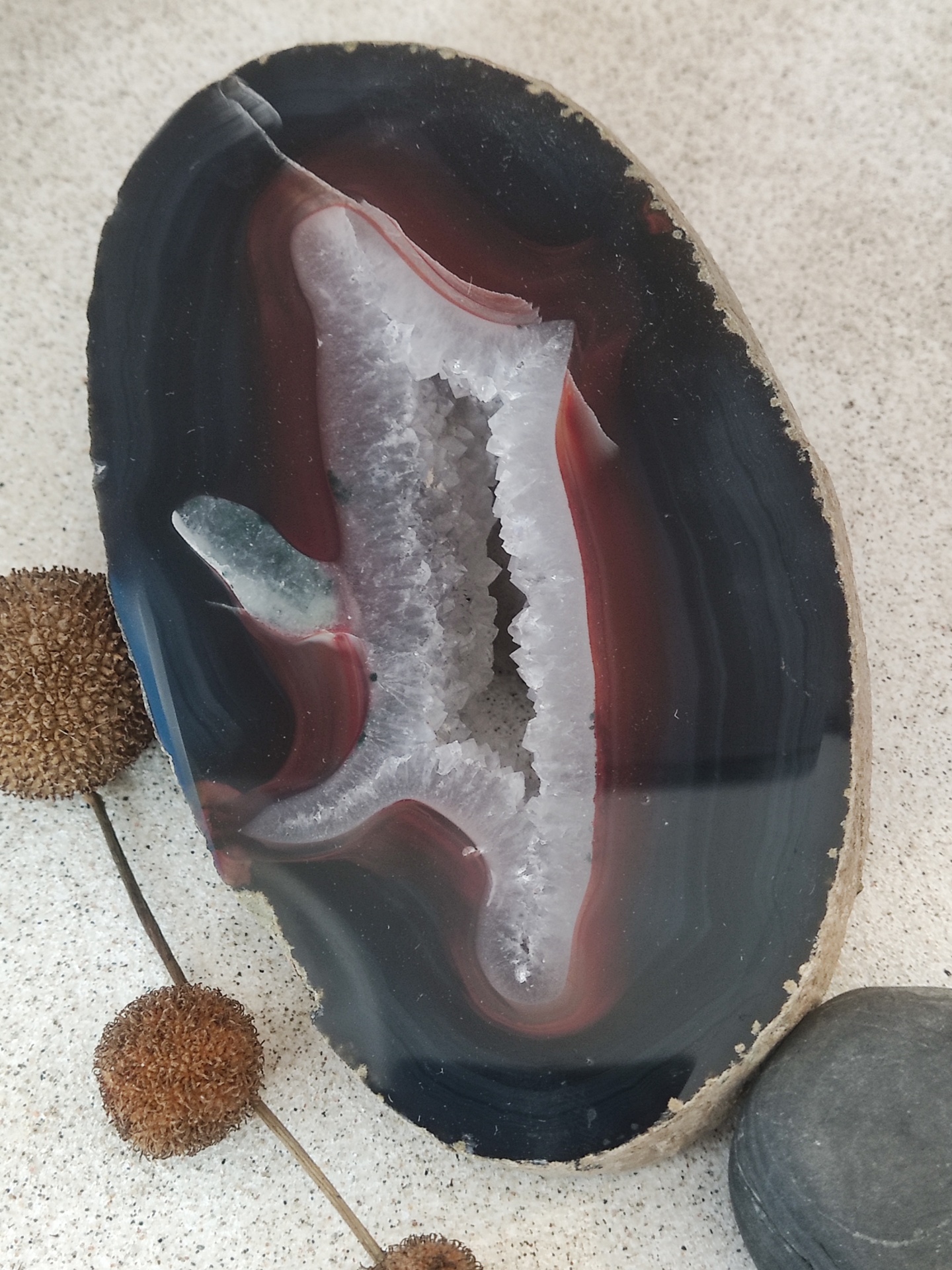 Agata cortada com interior cristalizado branco e bordas em tons de preto e vermelho