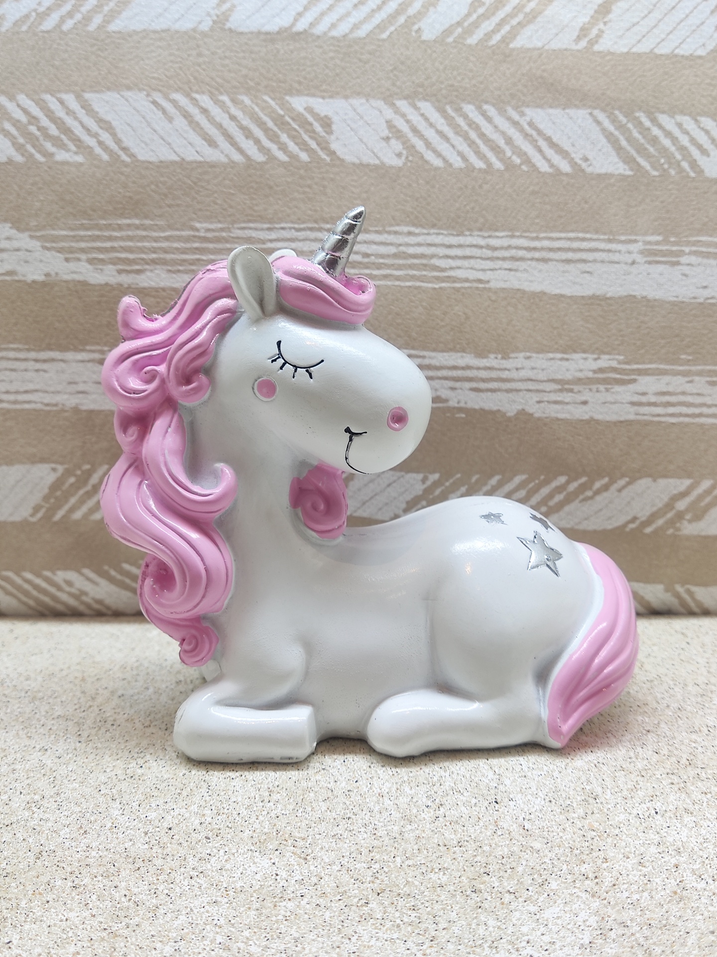 Estátua de unicórnio branco com crina e cauda cor-de-rosa e detalhes em prata.
