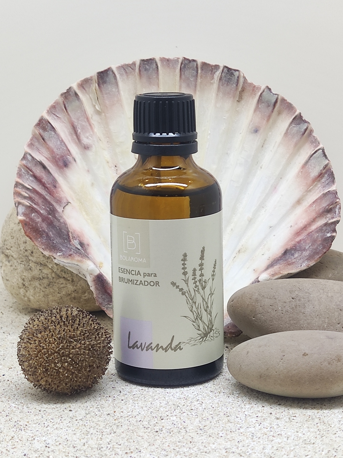 Frasco de essência de lavanda para brumizador sobre concha e pedras