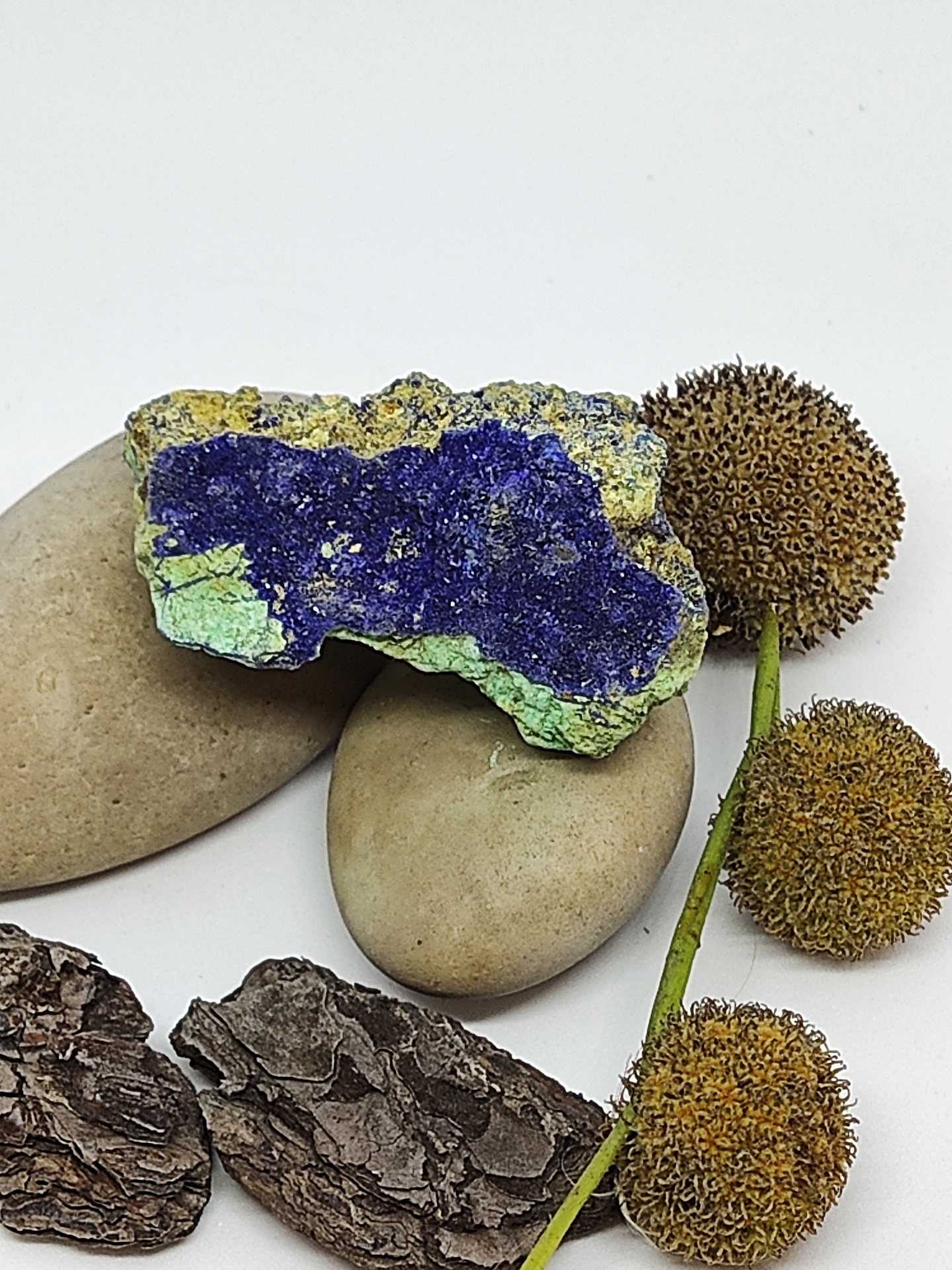 Pedras lisas, rocha com cores azul e verde, cascas de árvore e flores secas