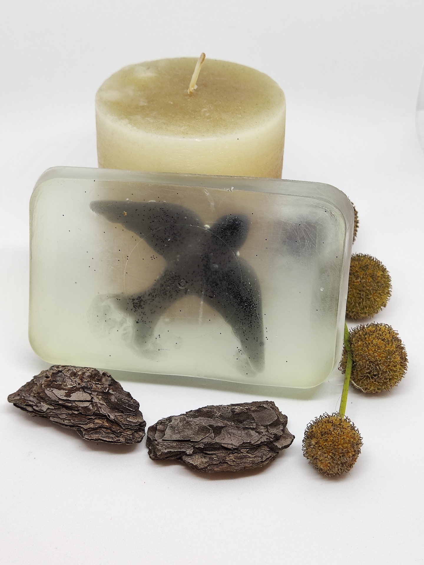 Sabonete transparente com pássaro preto embutido e vela bege com casca e frutos secos