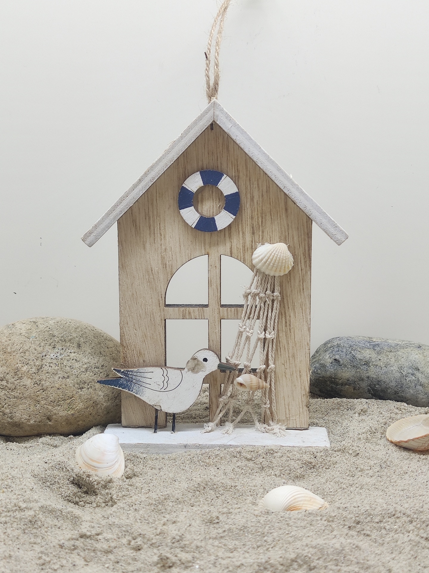 Decoração de casinha de madeira com gaivota e torre de conchas sobre areia