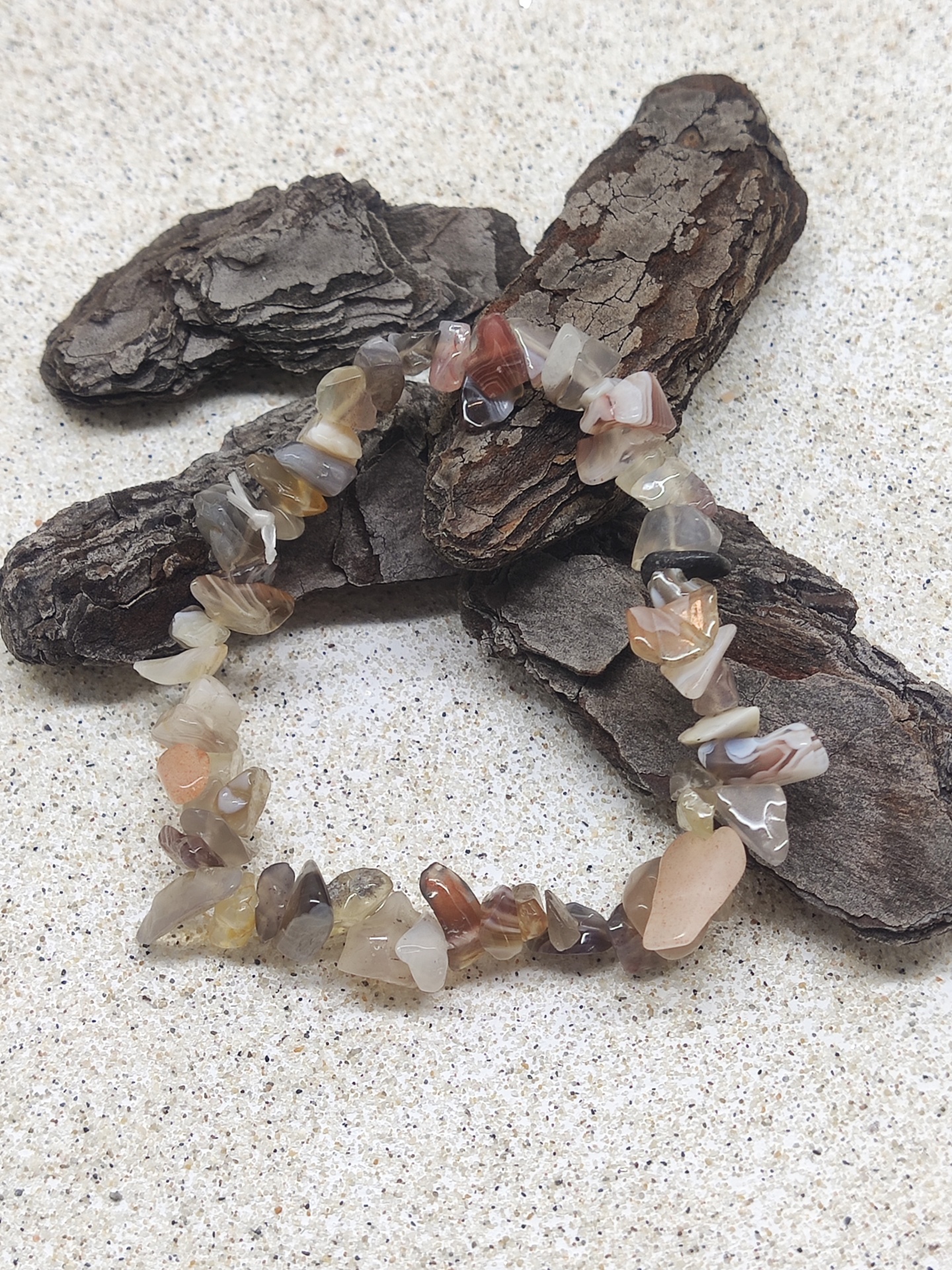 Pulseira de pedras naturais multicoloridas sobre casca de árvore