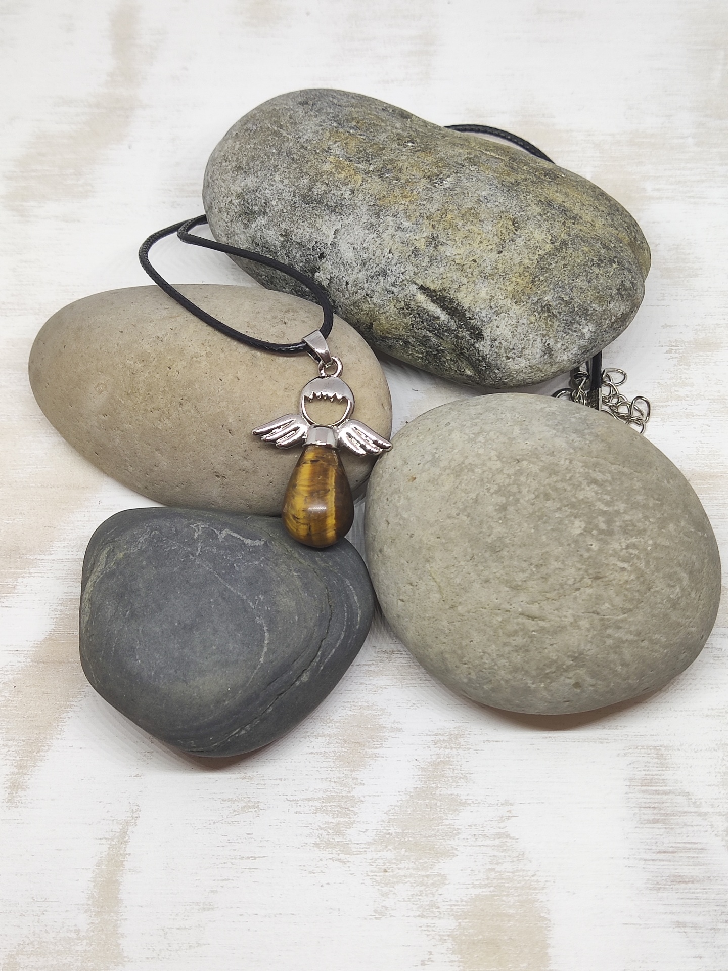 Colar com pendente em forma de anjo sobre pedras lisas