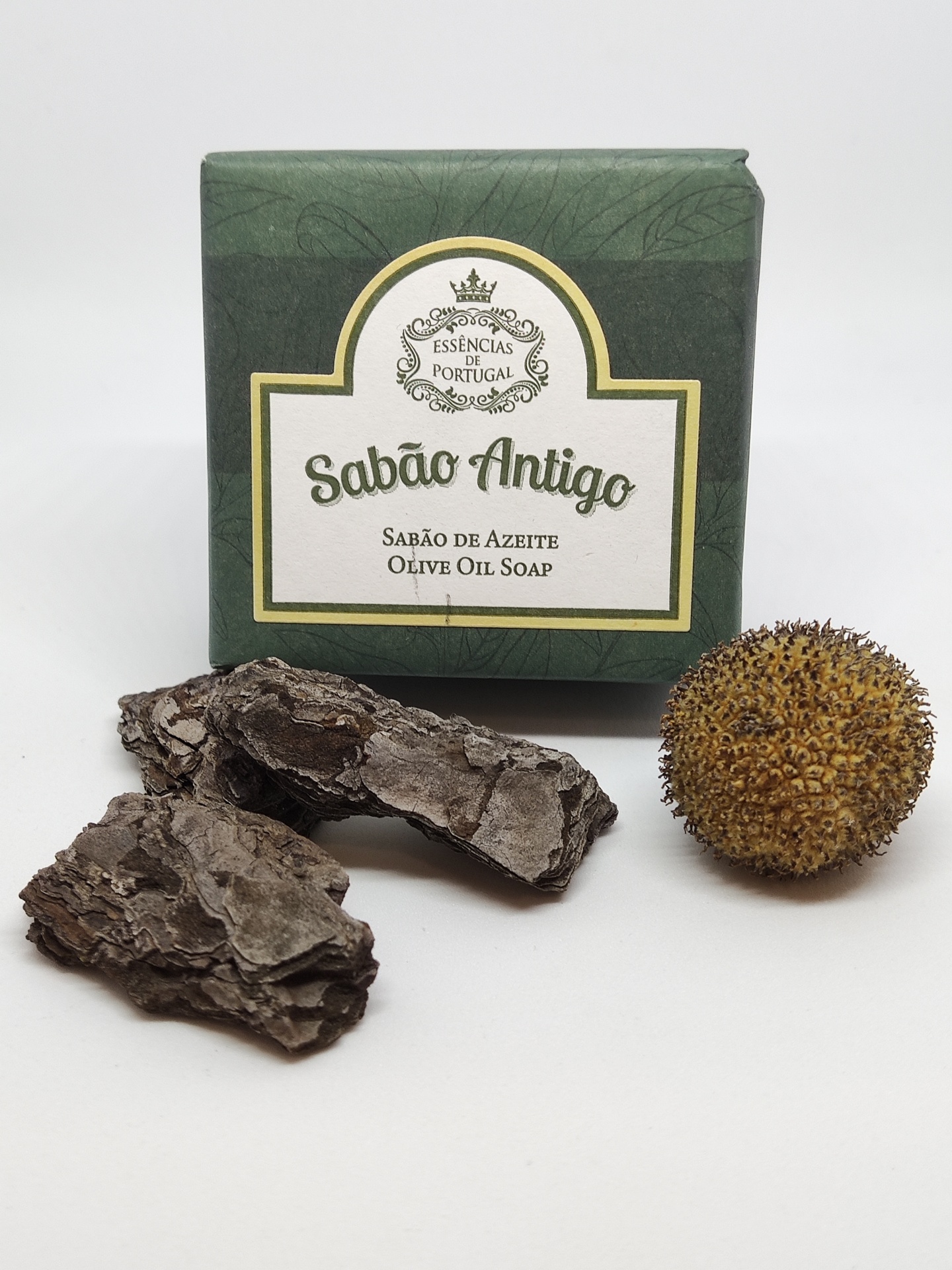 Sabonete Sabão Antigo embalado com casca de árvore e fruto seco ao lado.
