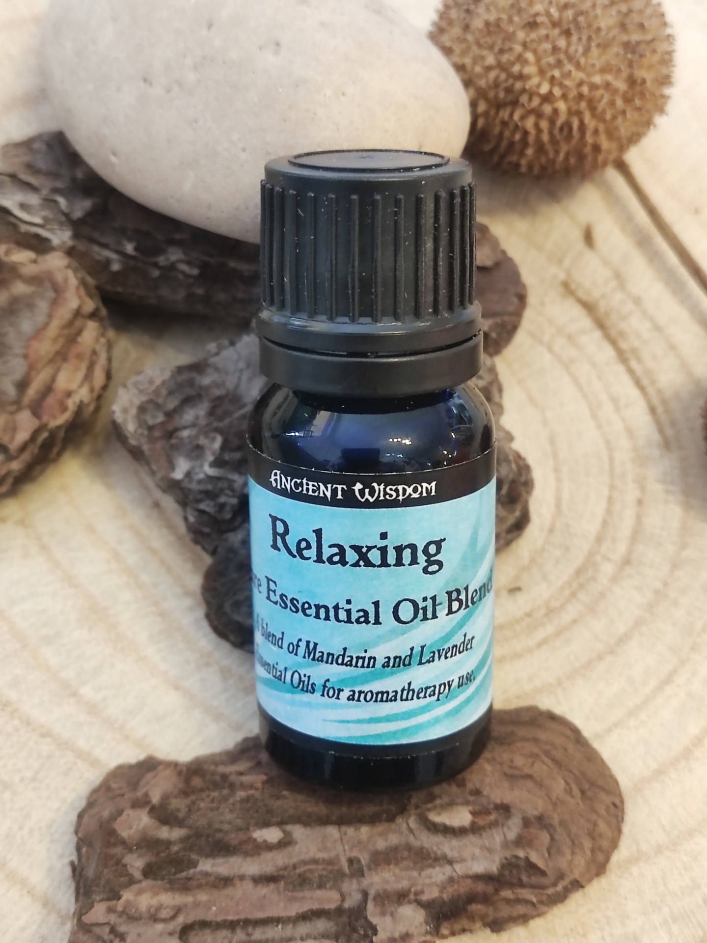 Frasco azul de óleo essencial Relaxing sobre madeira e cascas