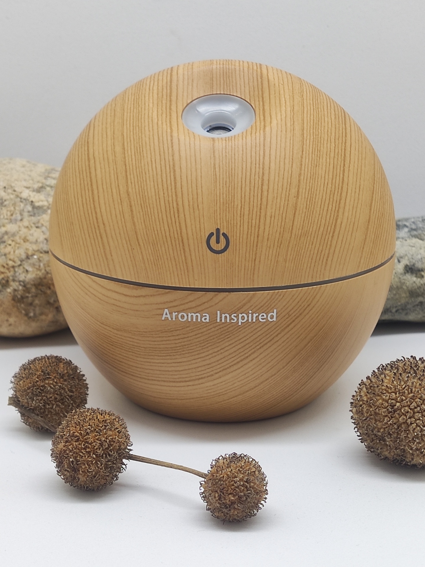 Difusor de aromas em madeira clara com texto 'Aroma Inspired' e botão de ligar
