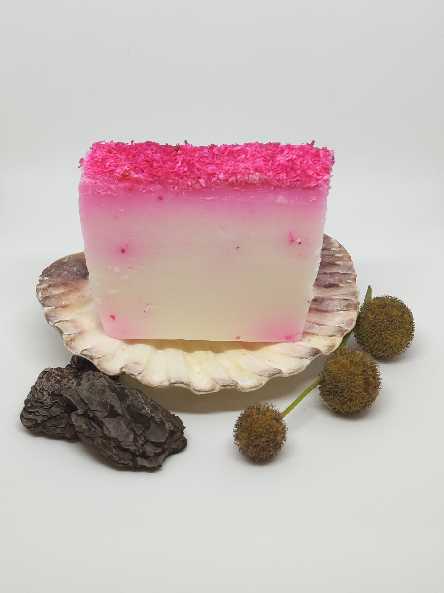Sabonete rosa e branco decorado sobre concha com casca e flores secas