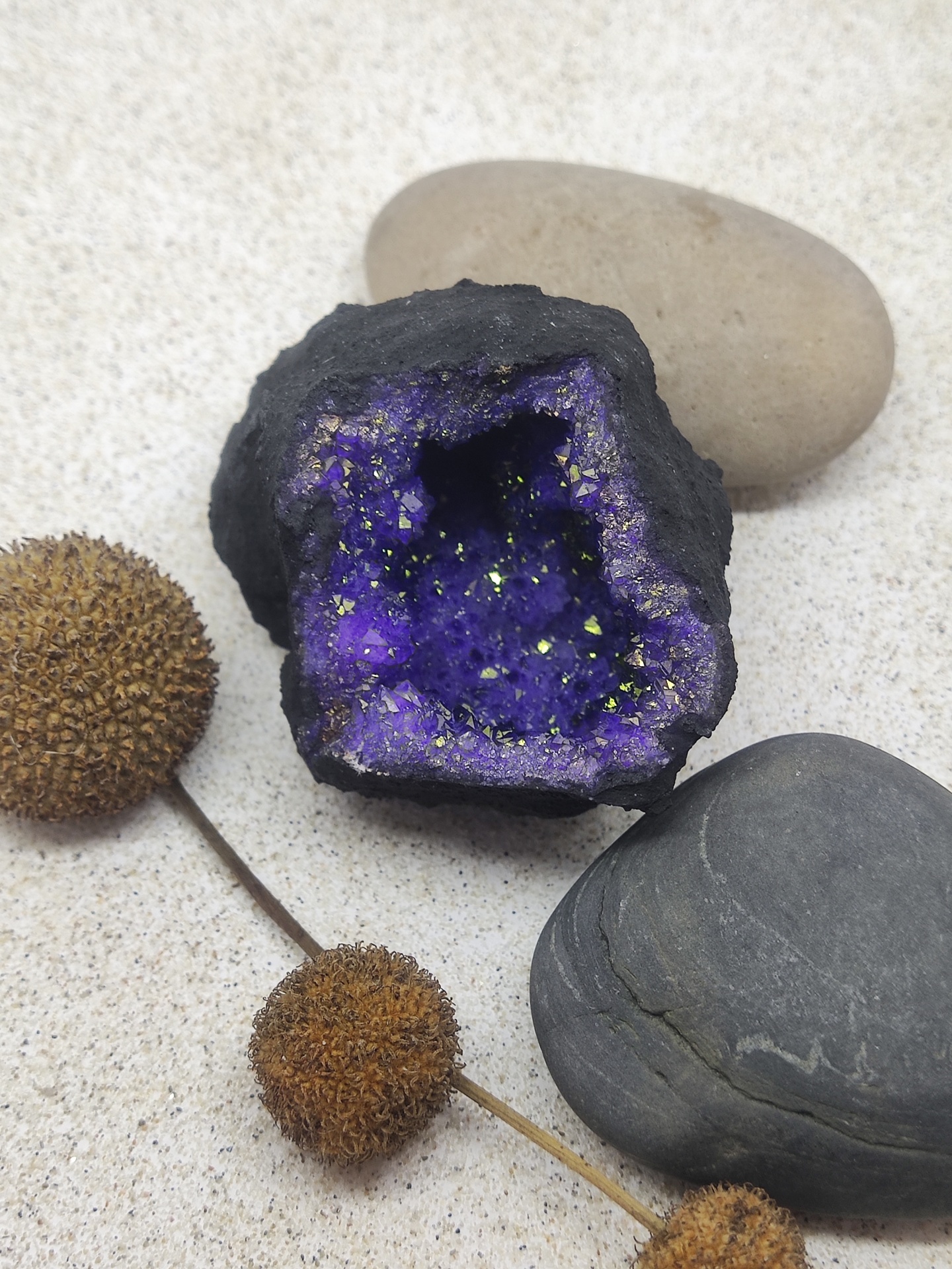 Geodo roxo cintilante com cristais dourados e pedras ao redor