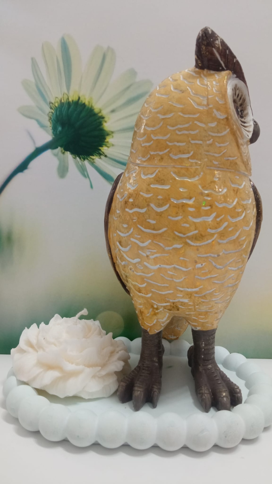 Estátua decorativa de coruja amarela com base branca e flor