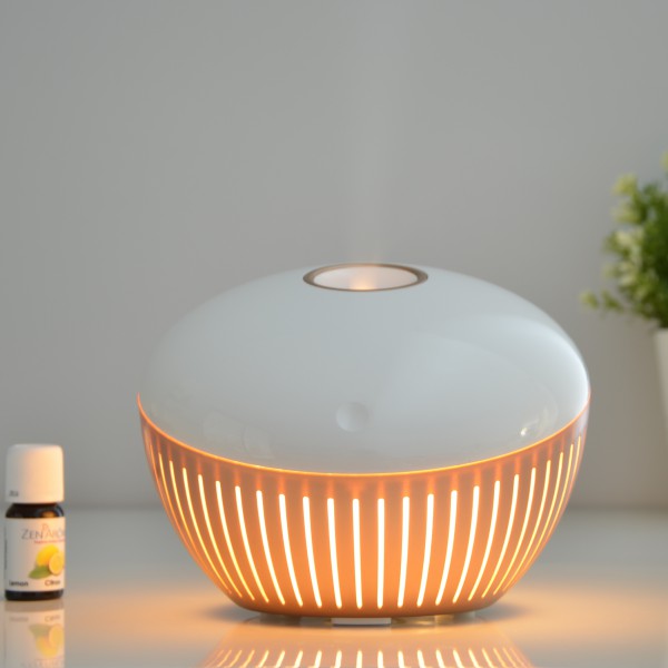 Difusor de aroma cerâmico branco com luz interior laranja numa superfície branca