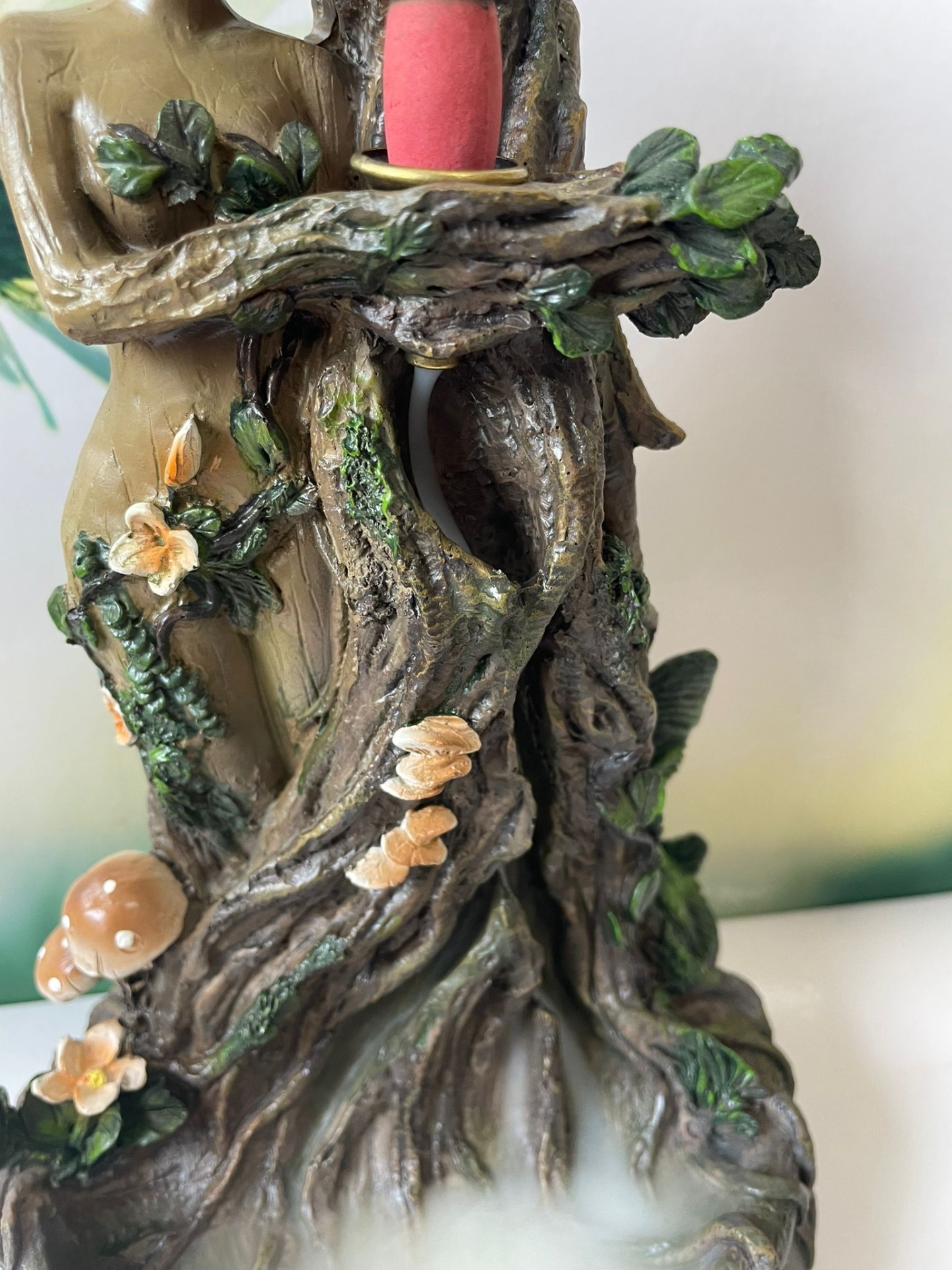 Escultura em resina de tronco de árvore com flores, cogumelos e vela vermelha