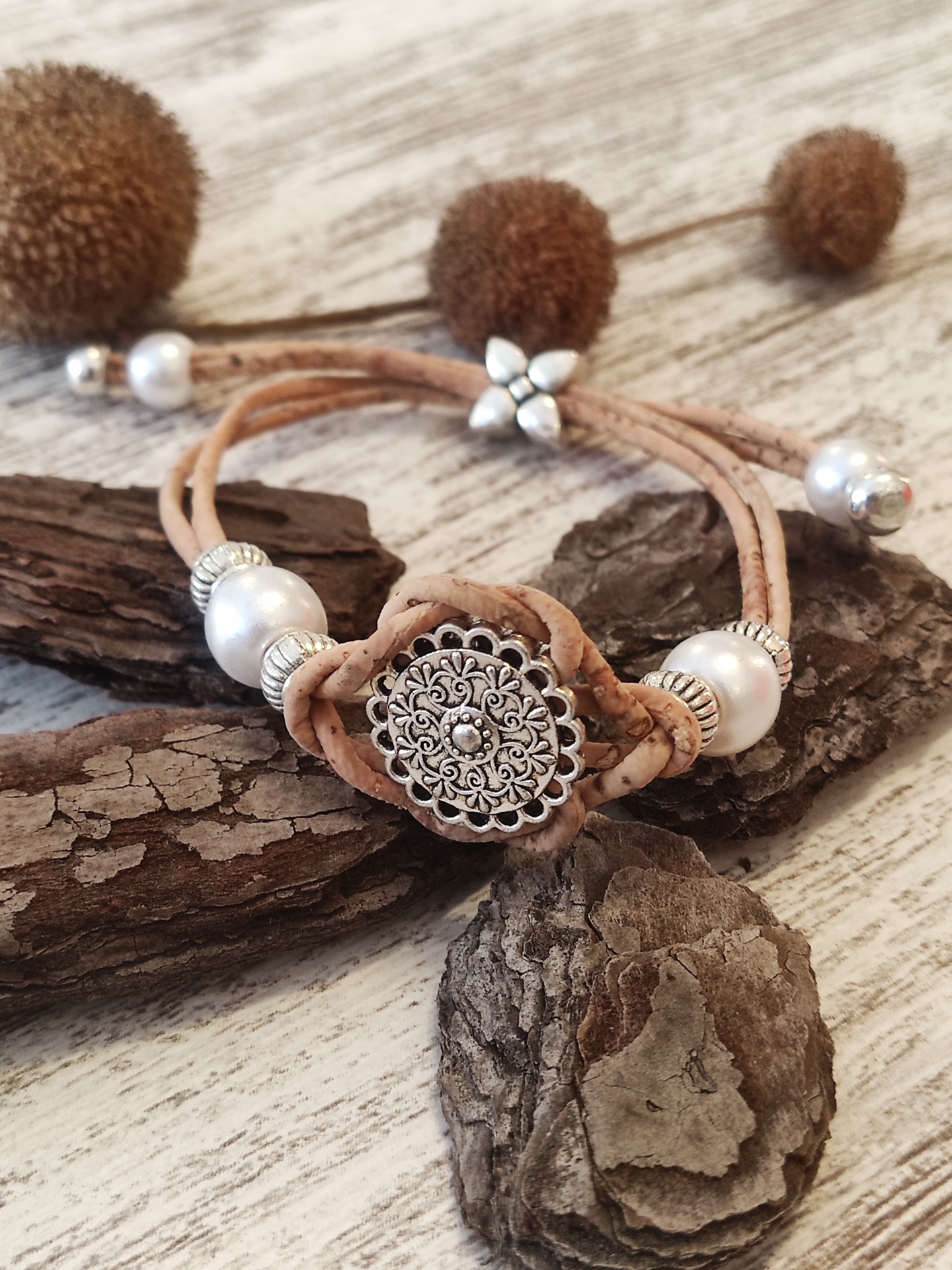 Pulseira bege com contas prateadas e pérolas sobre madeira clara e rústica