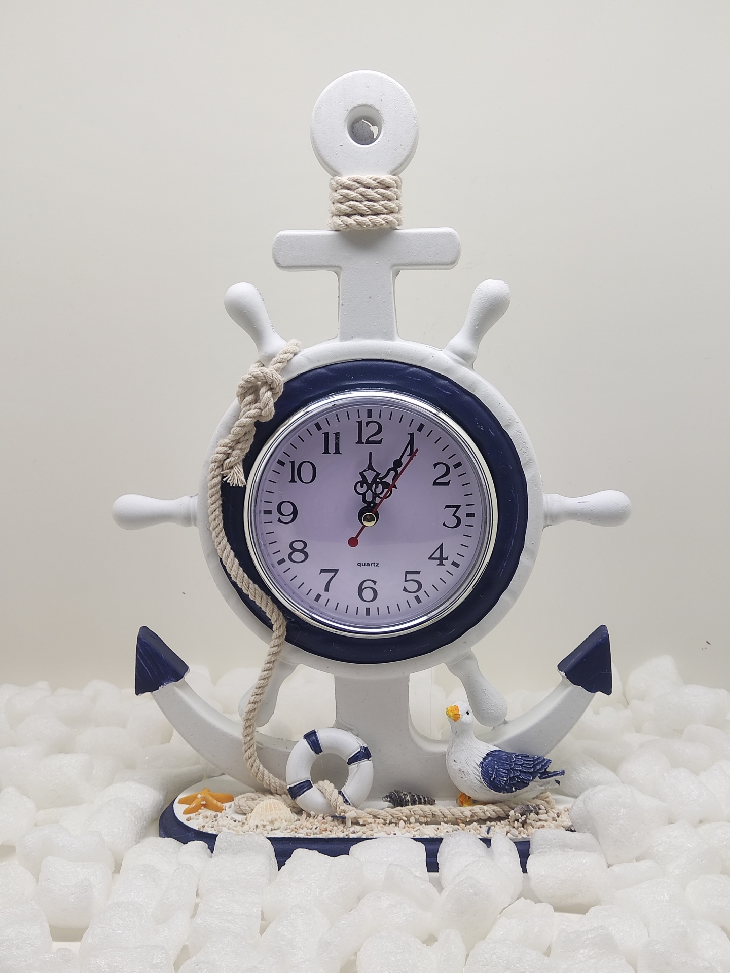 Relógio decorativo formato leme de navio com elementos marítimos e base azul e branca