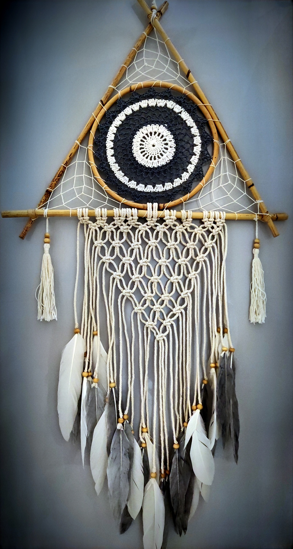 Apanhador de sonhos em madeira, fios de algodão branco e cinza e penas penduradas