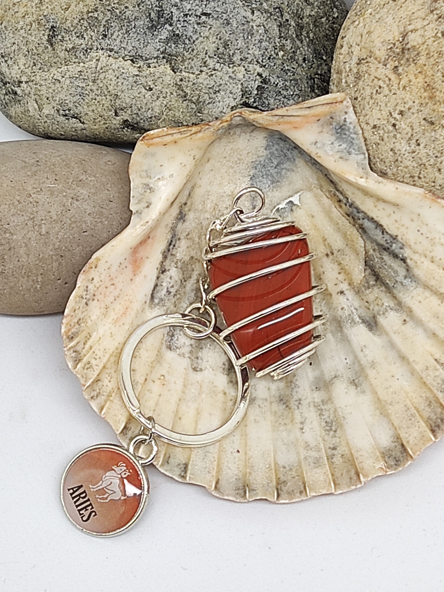 Chaveiro de pedra vermelha com arame e pendente Aries sobre concha