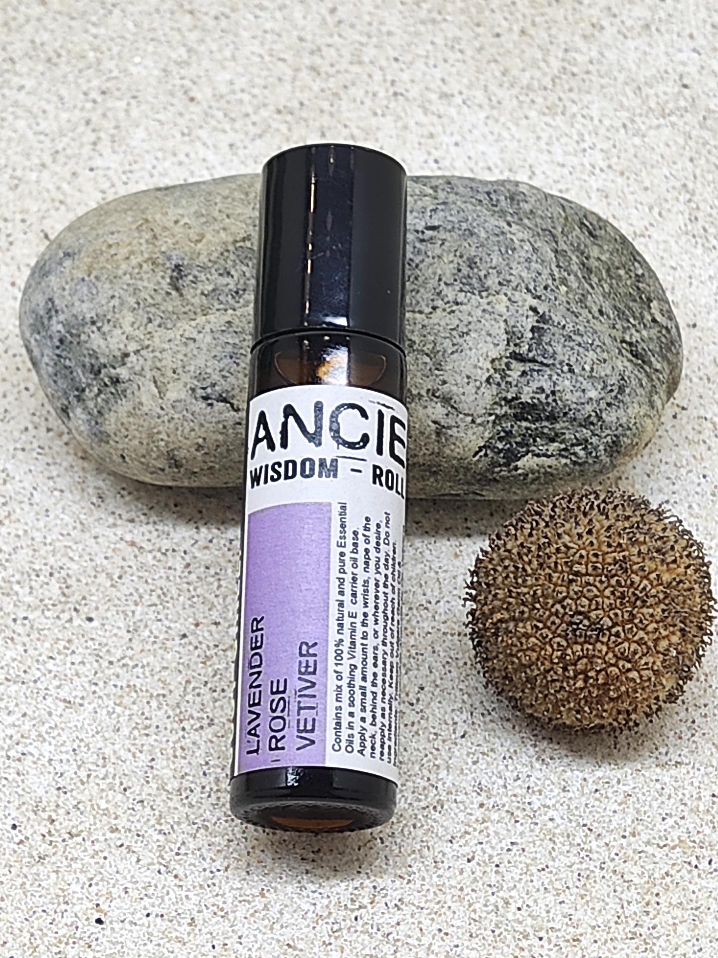 Frasco de óleo essencial roll-on com pedra e semente na superfície clara