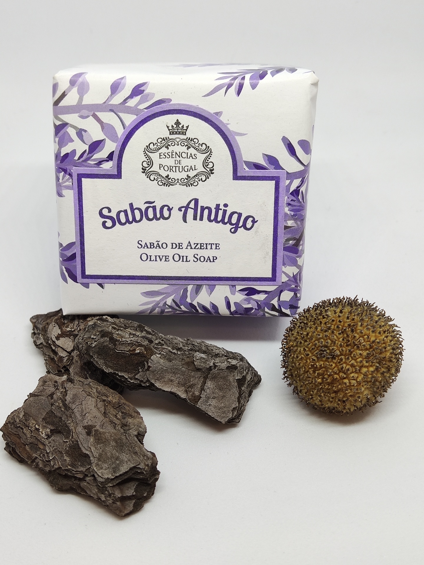 Sabão Antigo em embalagem branca com detalhes roxos e elementos naturais secos em fundo branco