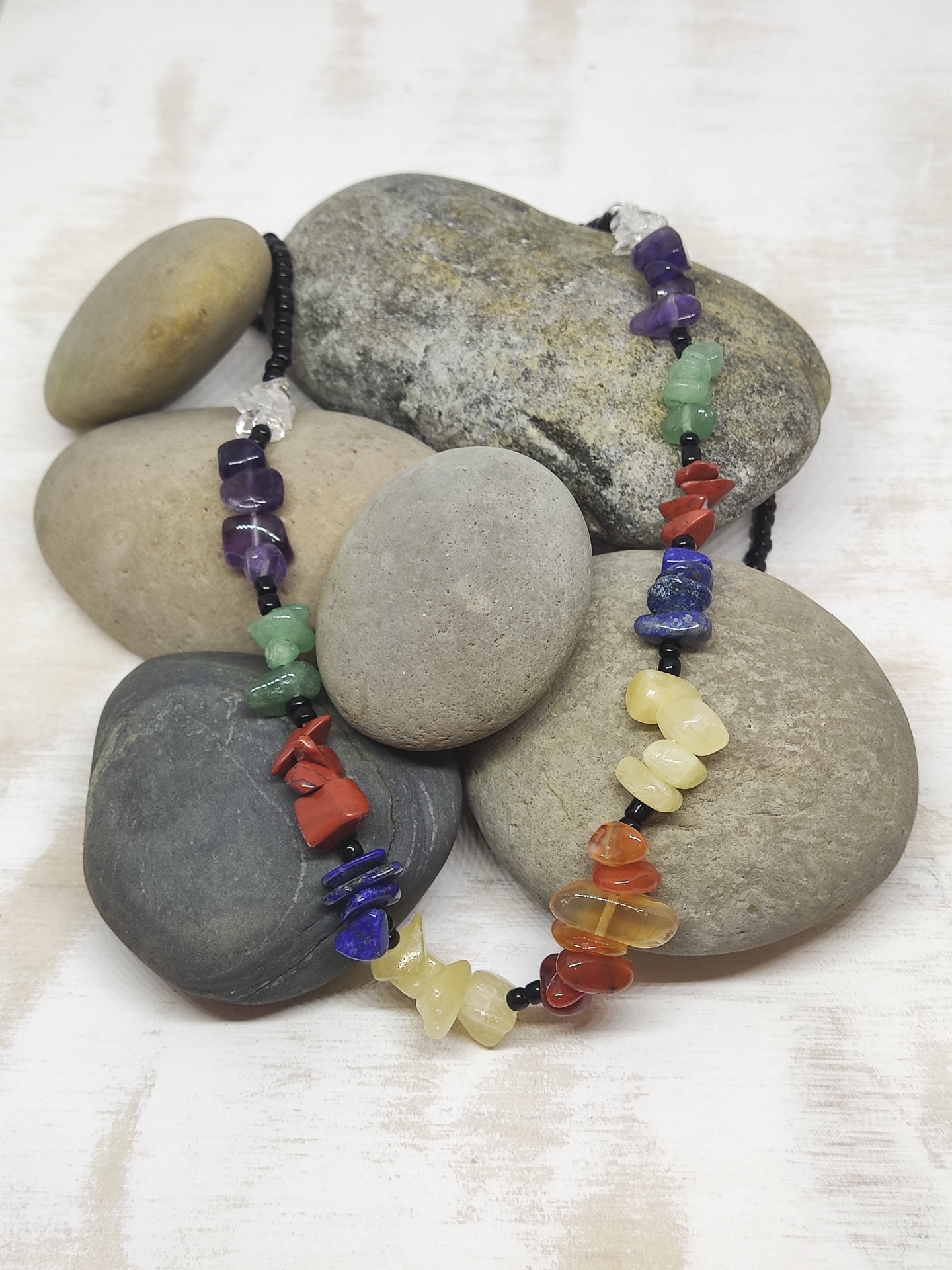Colar de pedras coloridas irregulares sobre pedras lisas cinzentas
