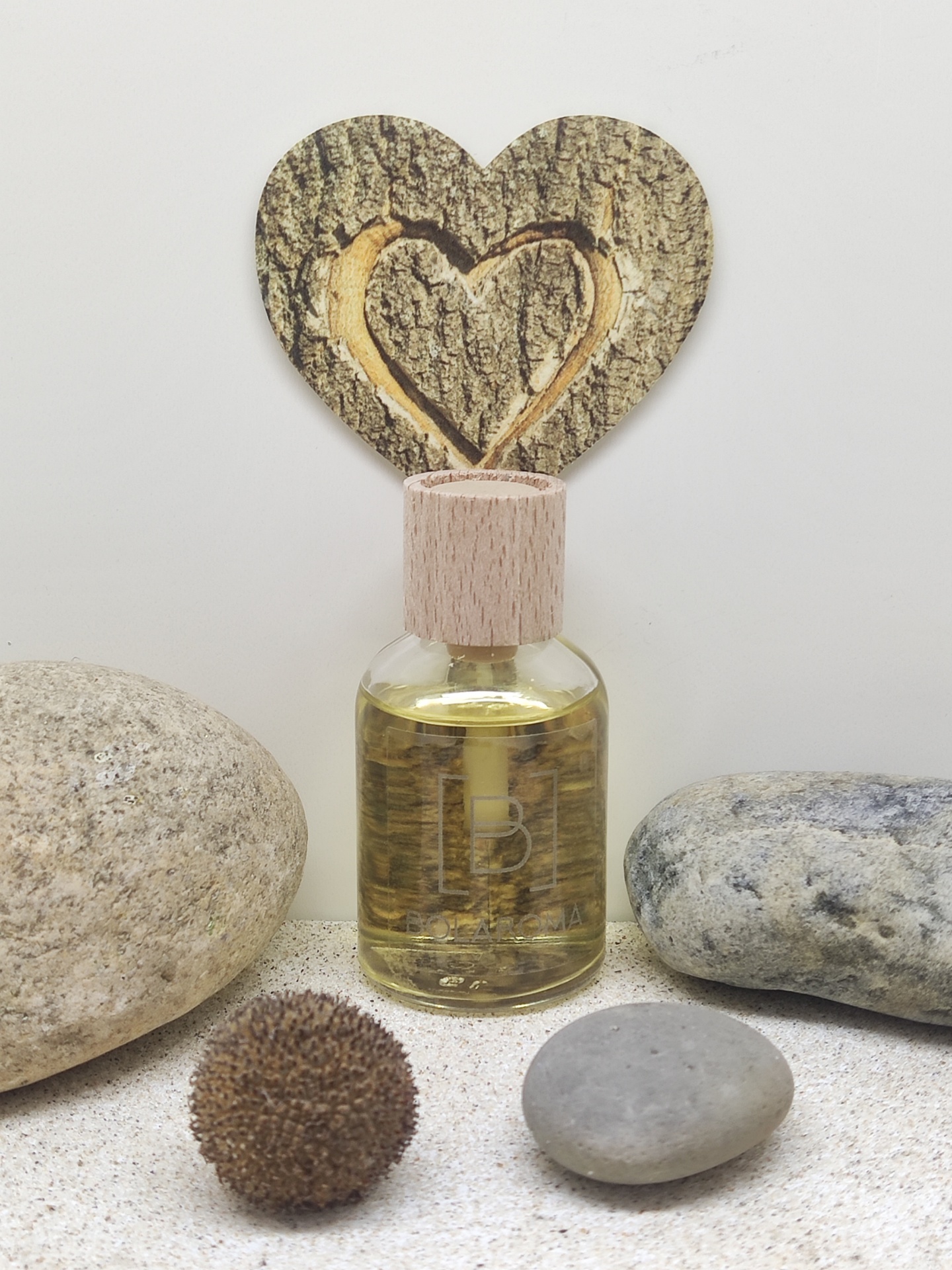 Frasco de vidro com tampa de madeira rodeado por pedras e decoração em forma de coração de madeira.
