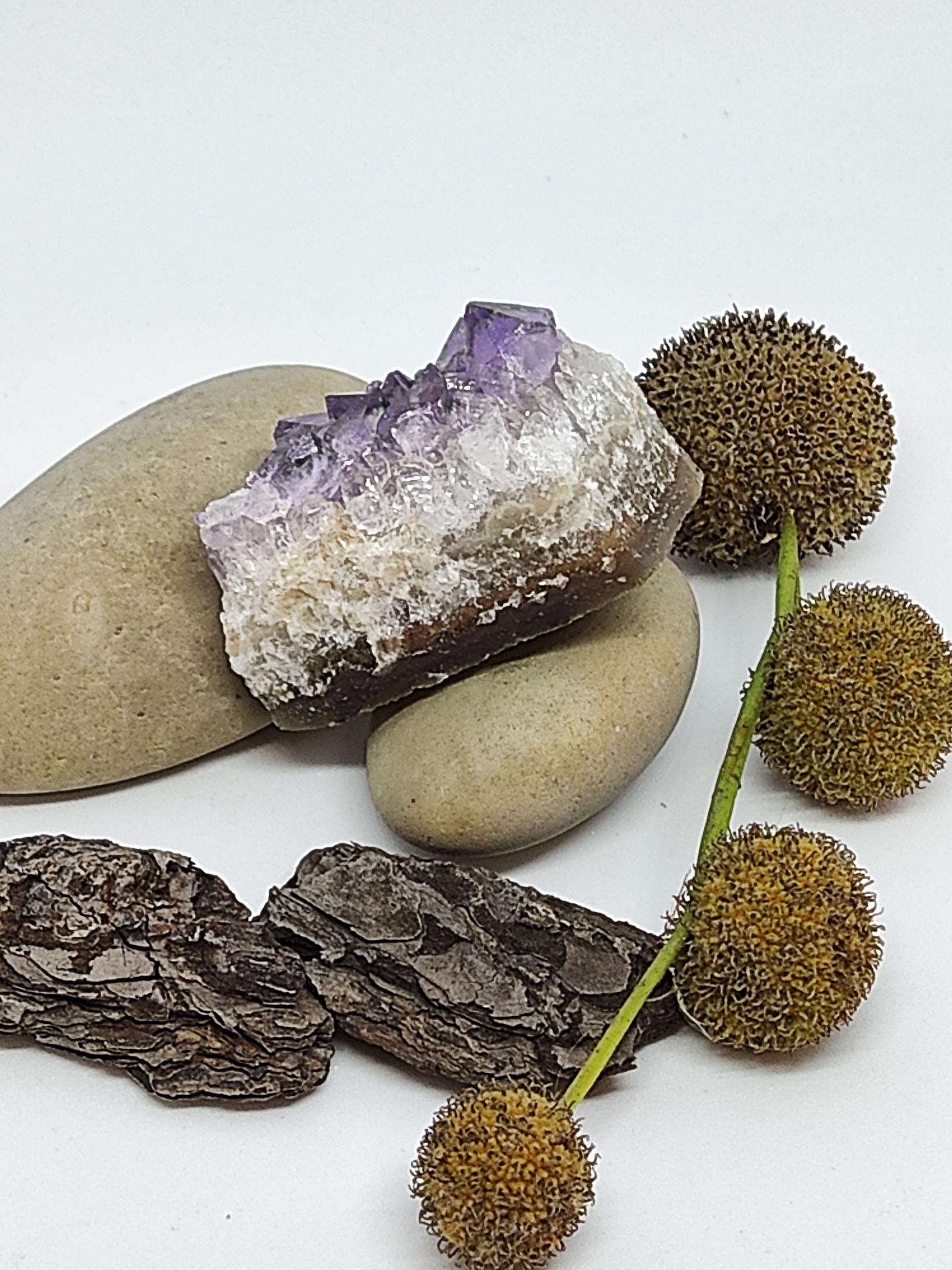 Cristal ametista com pedras, casca de árvore e bolas secas sobre fundo branco
