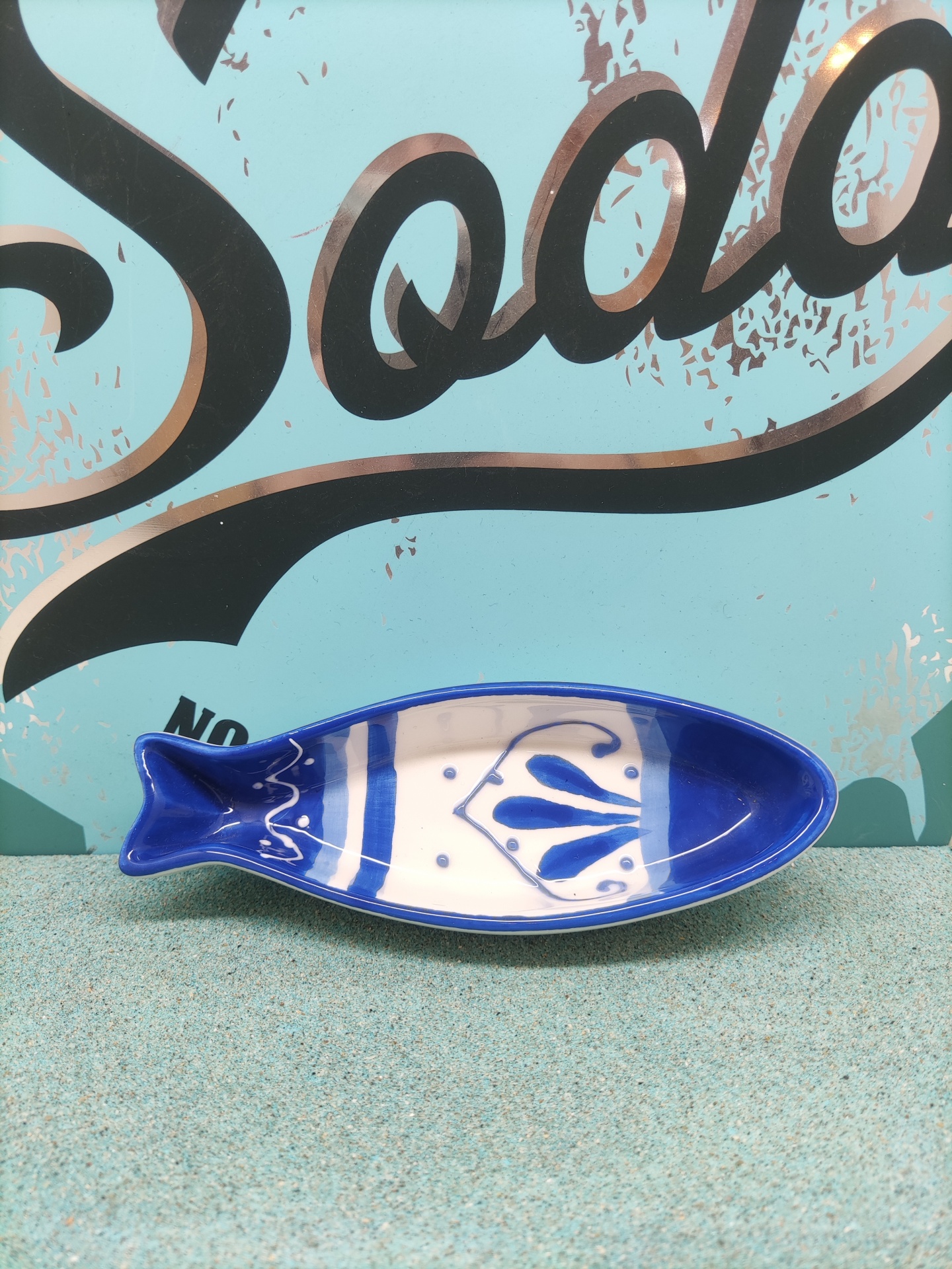 Prato de cerâmica azul e branco em forma de peixe com padrão decorativo