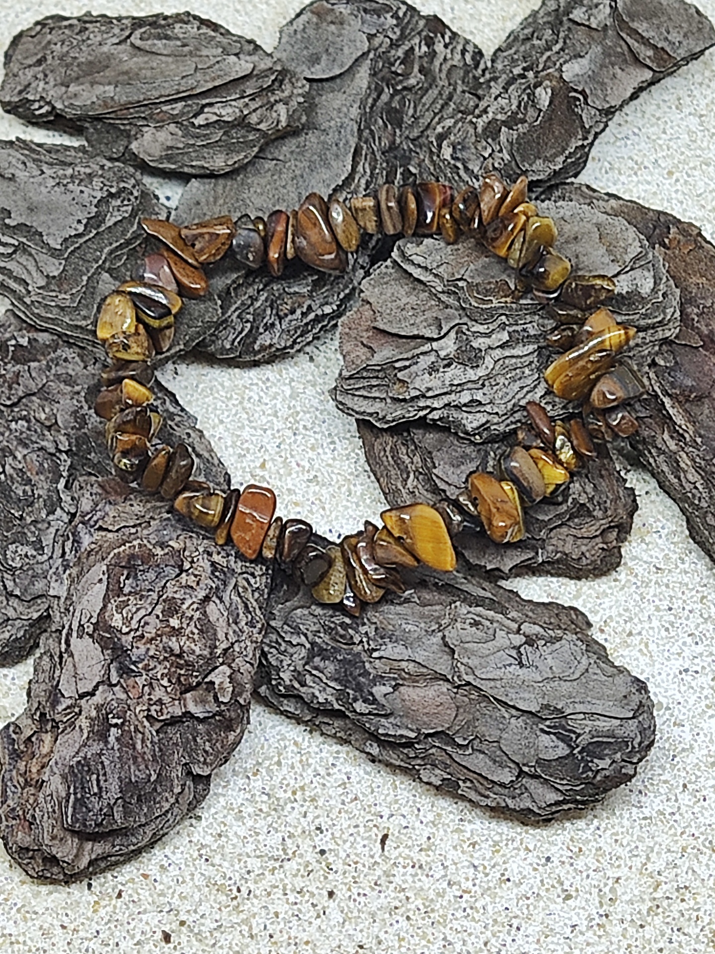 Pulseira de pedras castanhas e amarelas sobre casca de árvore