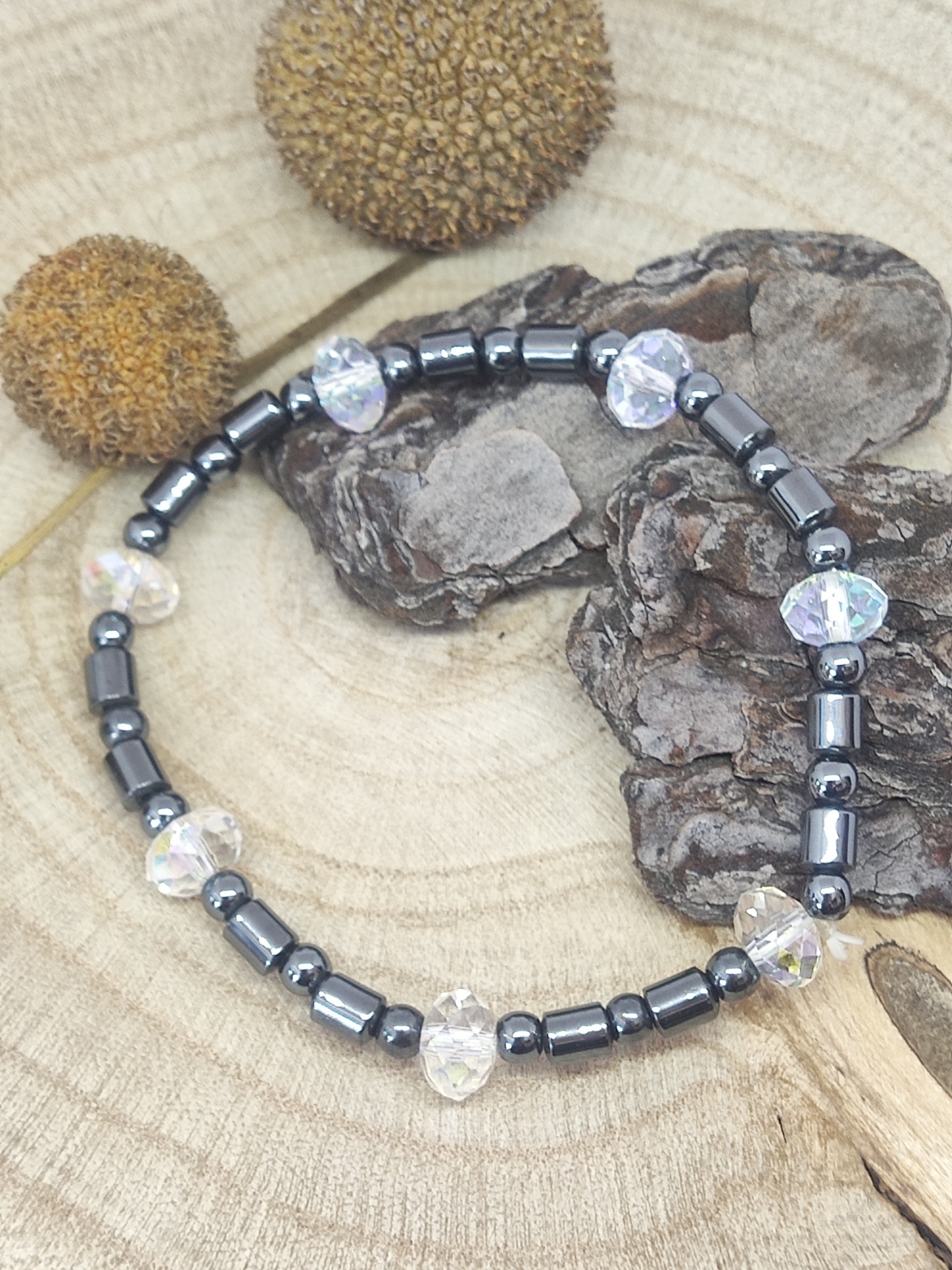 Pulseira com contas pretas e corações translúcidos sobre madeira rústica