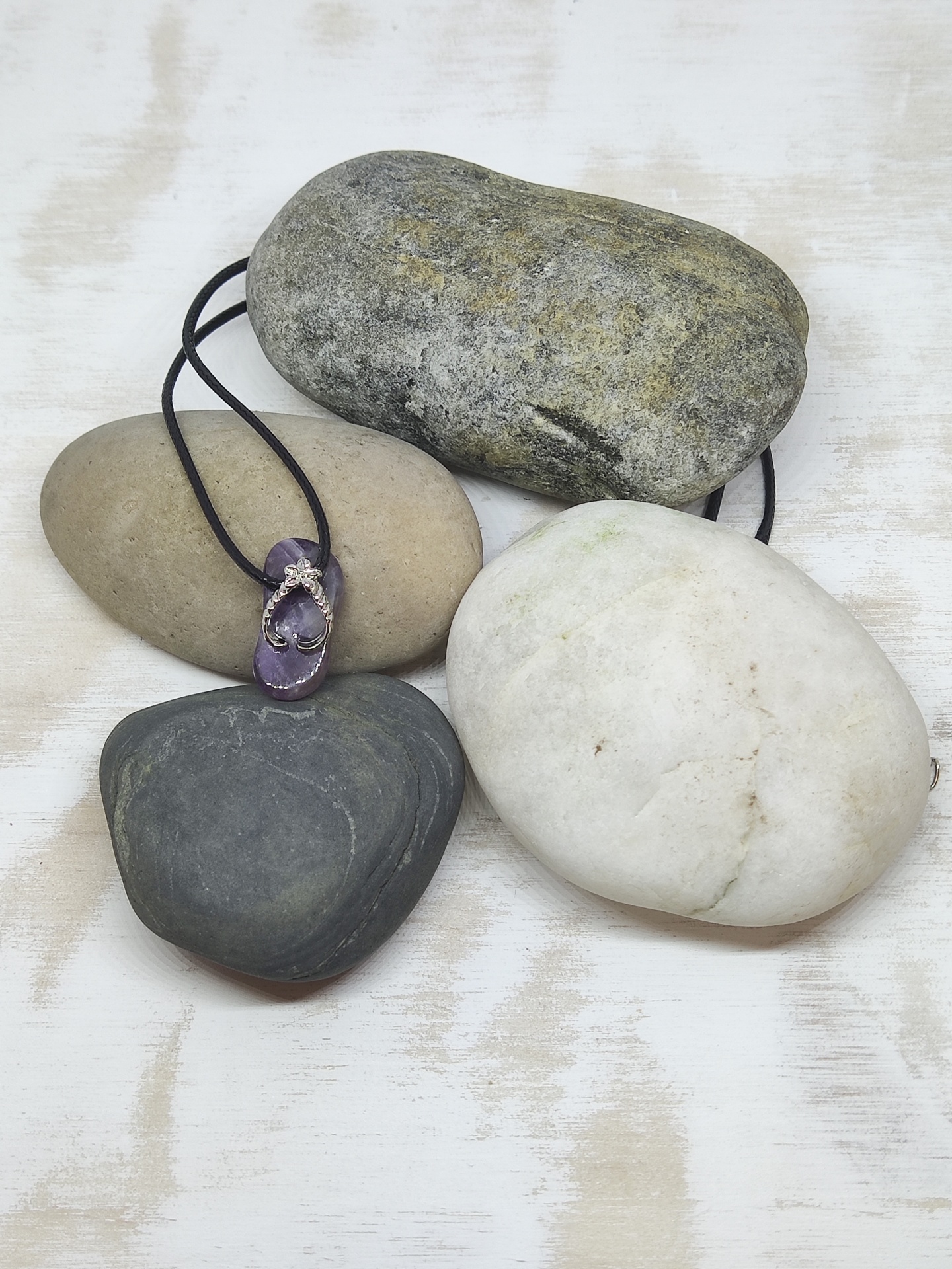 Colar com pendente de pedra roxa e cordão preto sobre pedras naturais coloridas