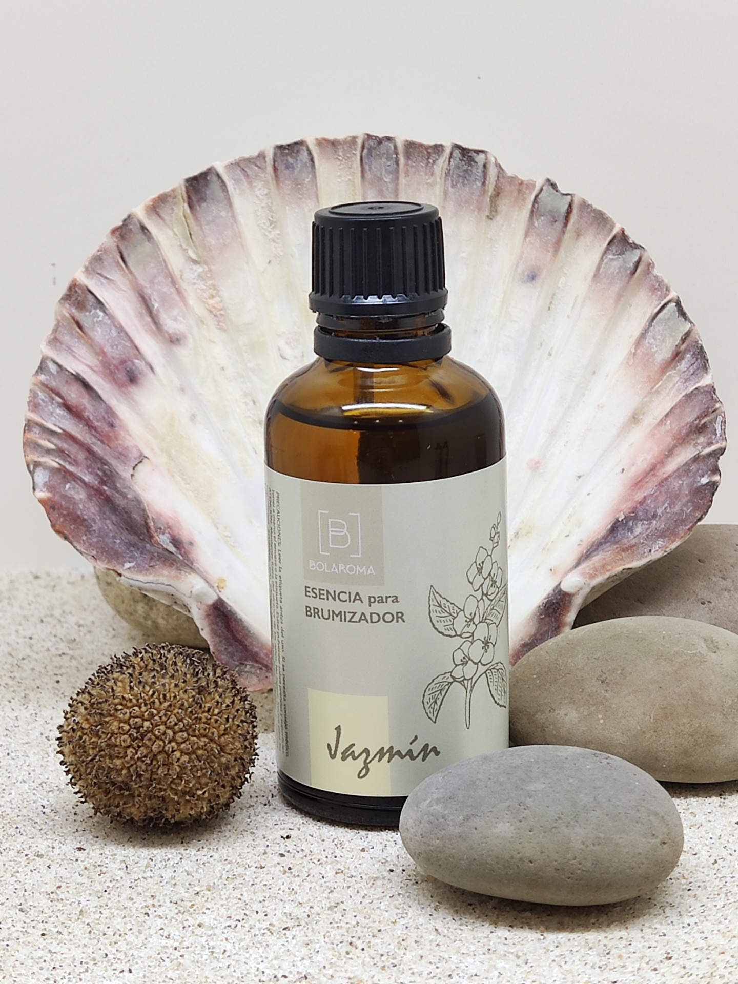 Frasco âmbar de essência para brumizador com concha e pedras em fundo de areia