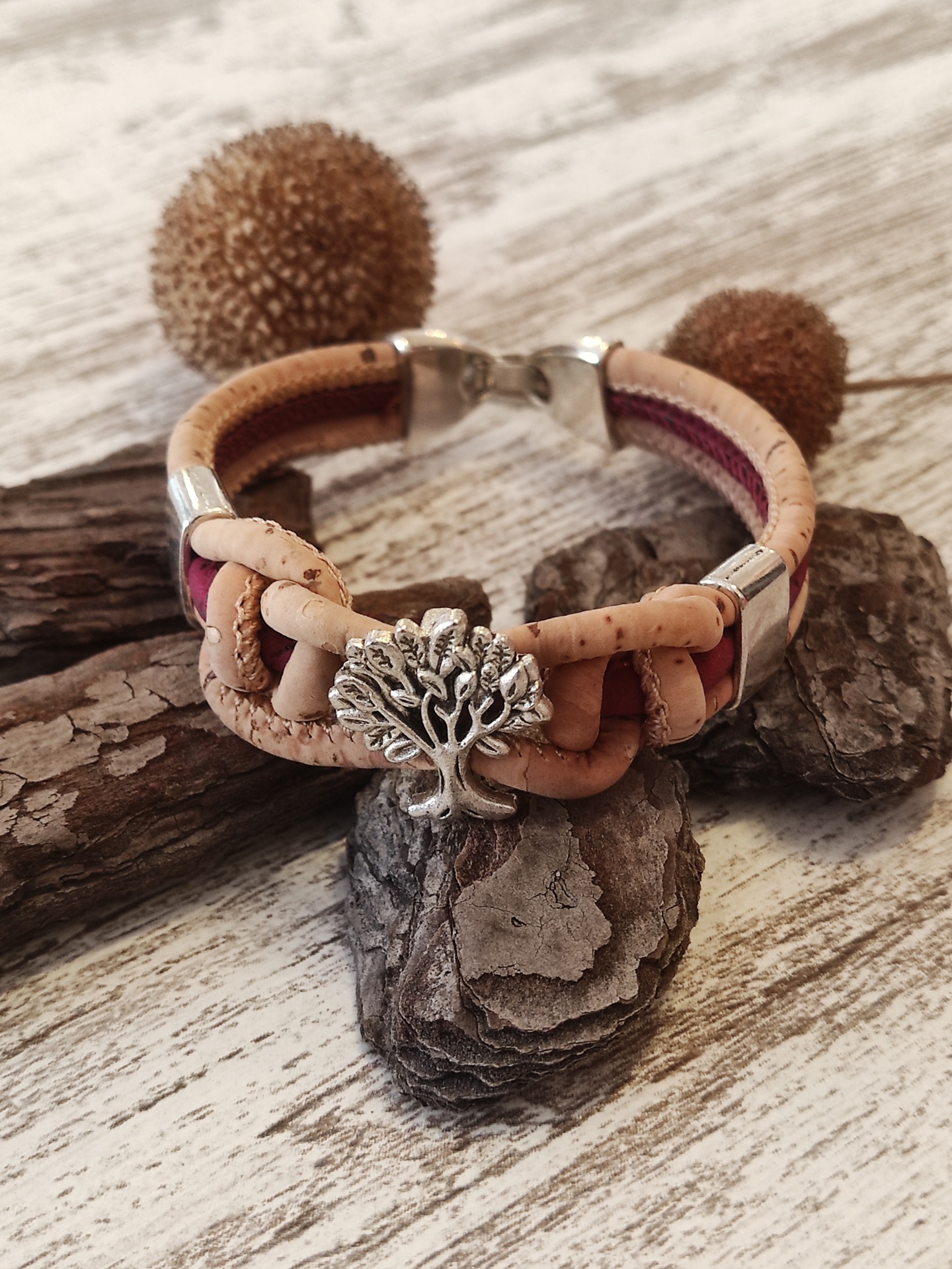 Pulseira de cortiça com pendente de árvore e tecido bordeaux sobre madeira clara
