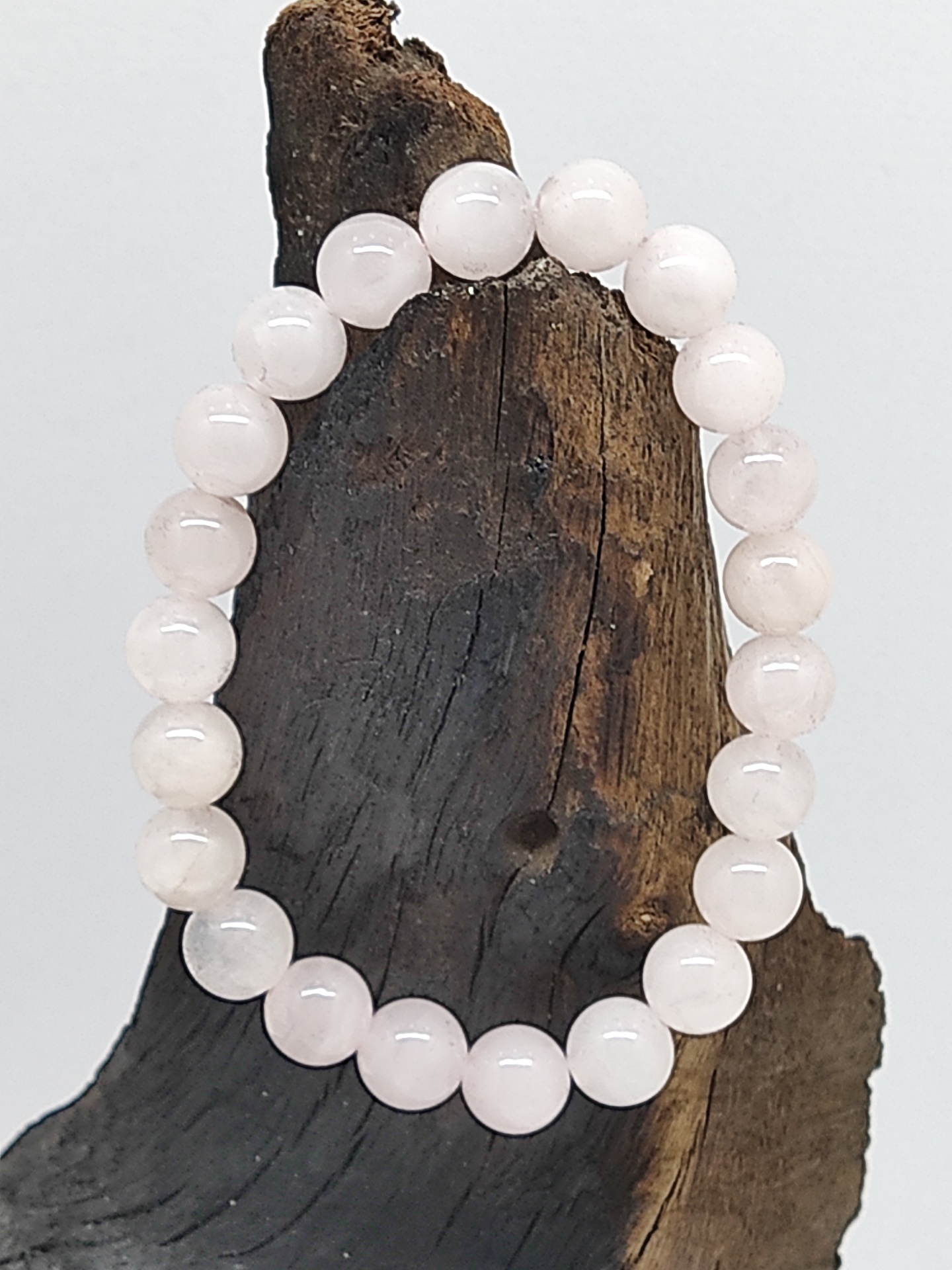 Pulseira de contas de pedra rosa clara sobre madeira castanha rugosa