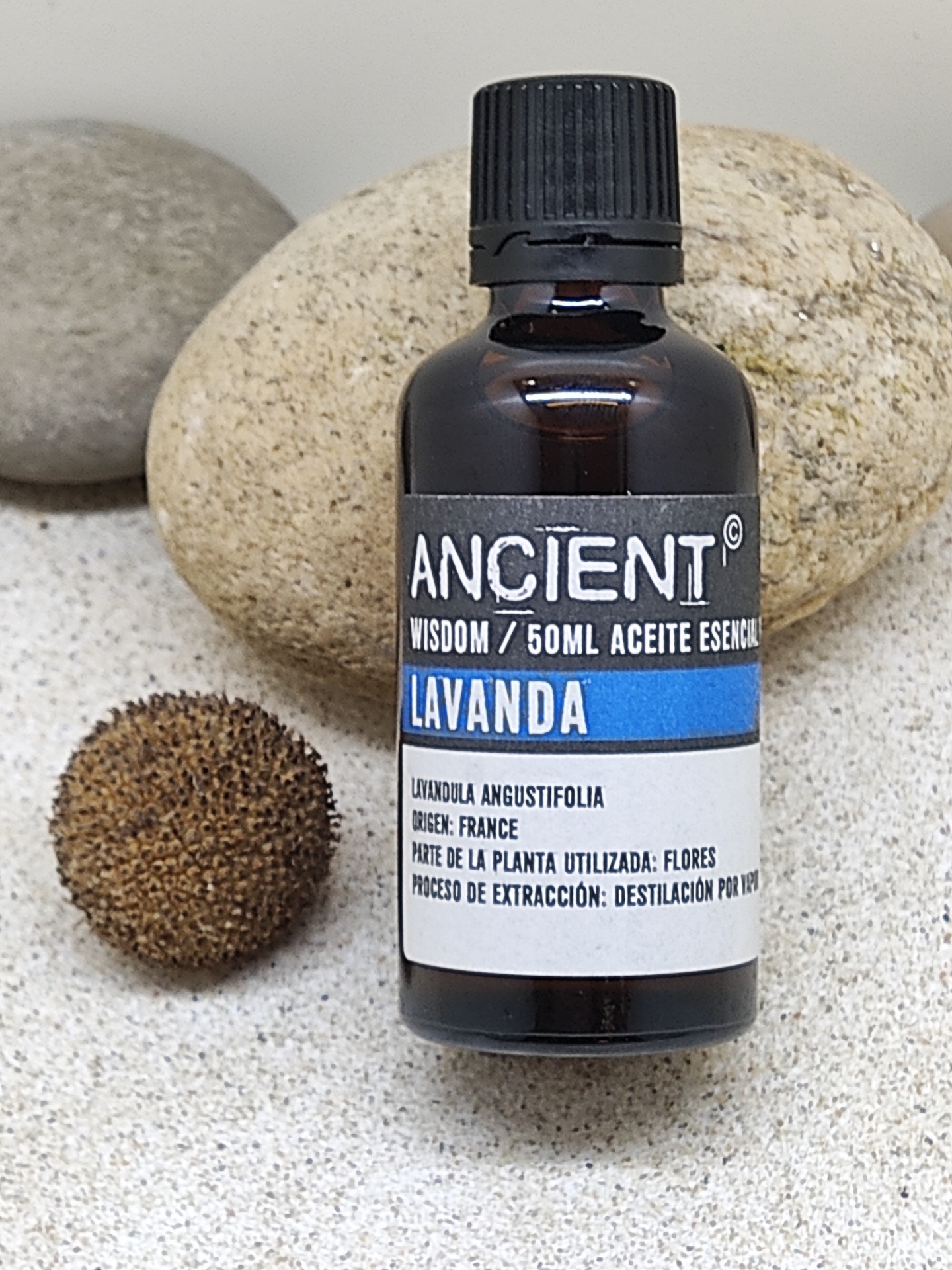 Frasco de óleo essencial de lavanda ANCIENT com pedras ao fundo