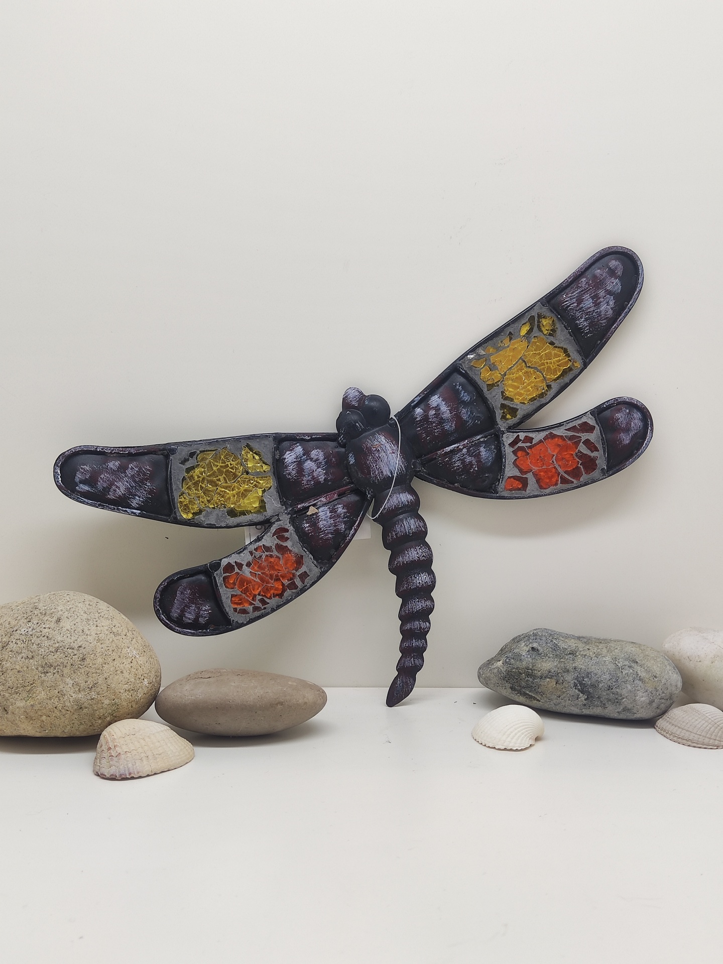 Decoração de parede em forma de libélula com pedras e conchas ao redor