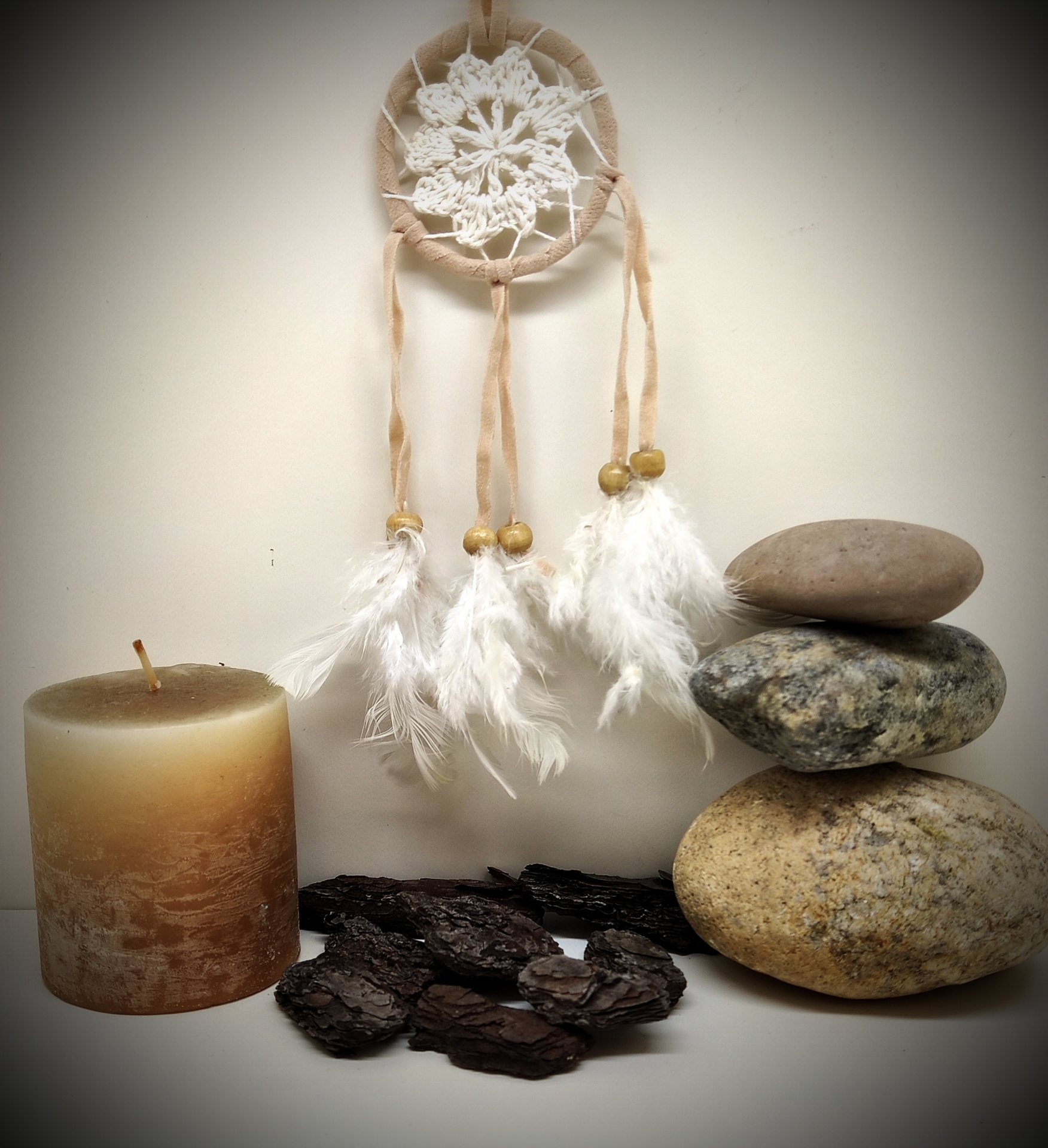 Decoração com filtro dos sonhos, vela, casca e pedras empilhadas